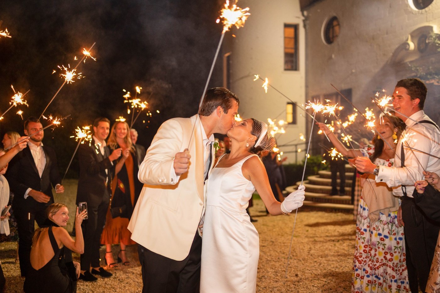 Bride and groom kissing while holding sparklers at their wedding send-off