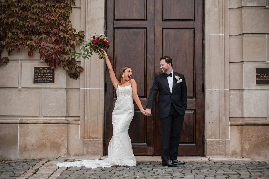 Bride and groom posing in front of grand wooden doors with cobblestones, showcasing a timeless estate for where to get married in New York.
