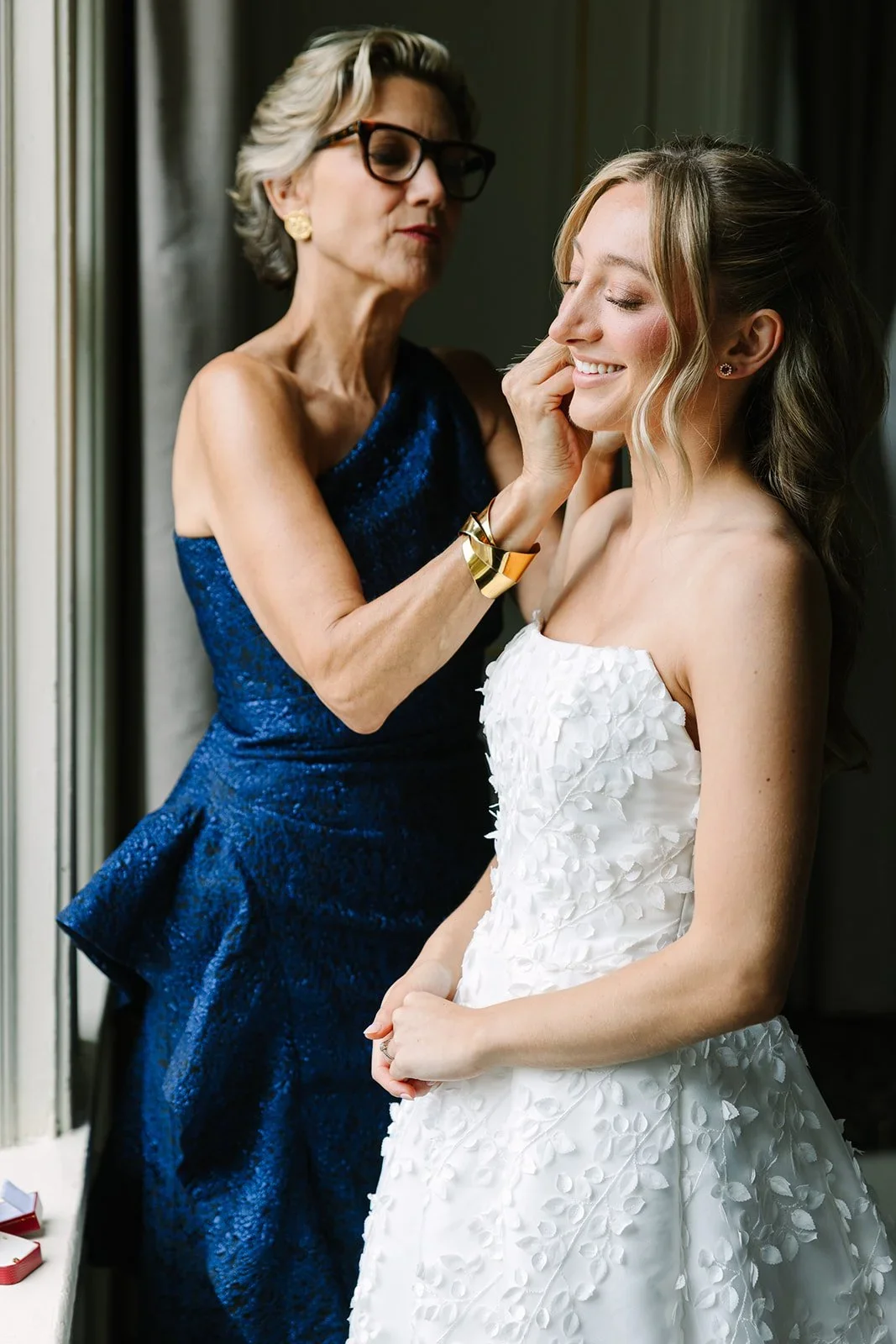 Mother of the bride gently helping her daughter prepare on the morning of their jewish wedding in New York