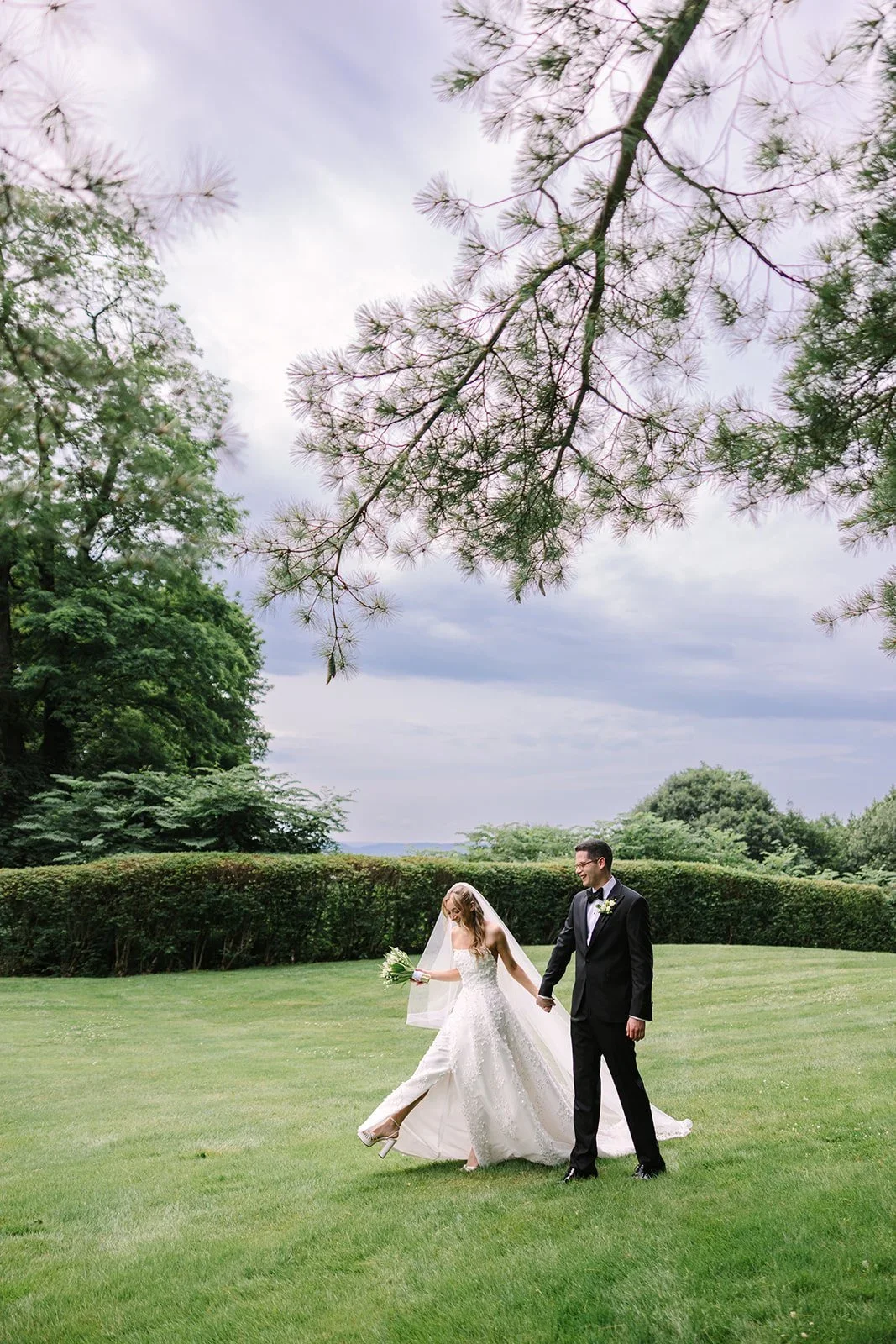 Bride and groom walking hand in hand through the garden surrounded by lush greenery