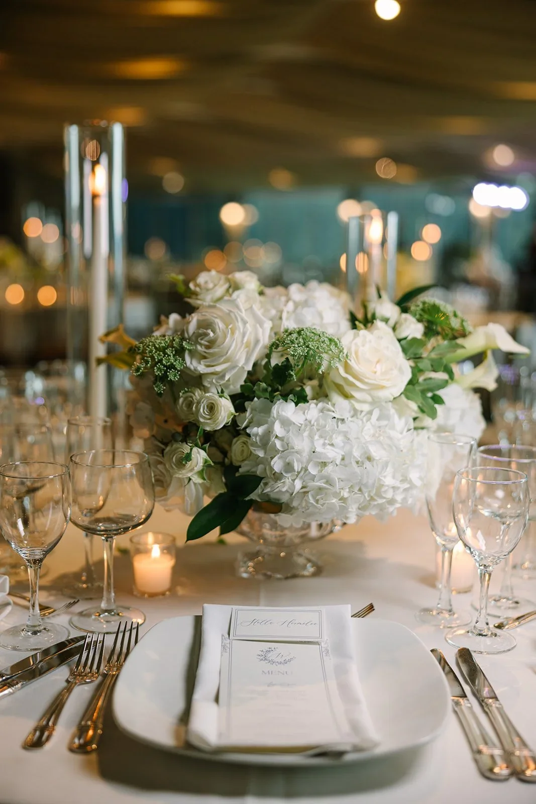 Guest table details featuring white linens, glassware, and soft candlelight