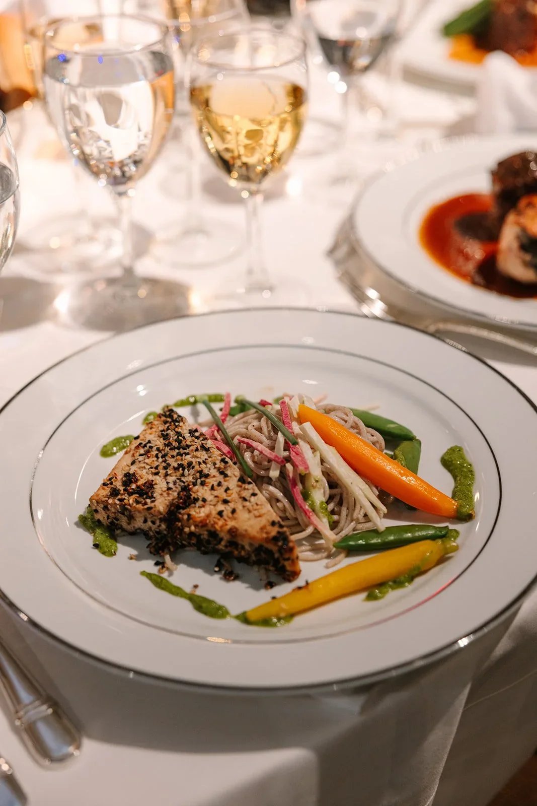 Dinner service underway with plated entrées and guests seated at long tables