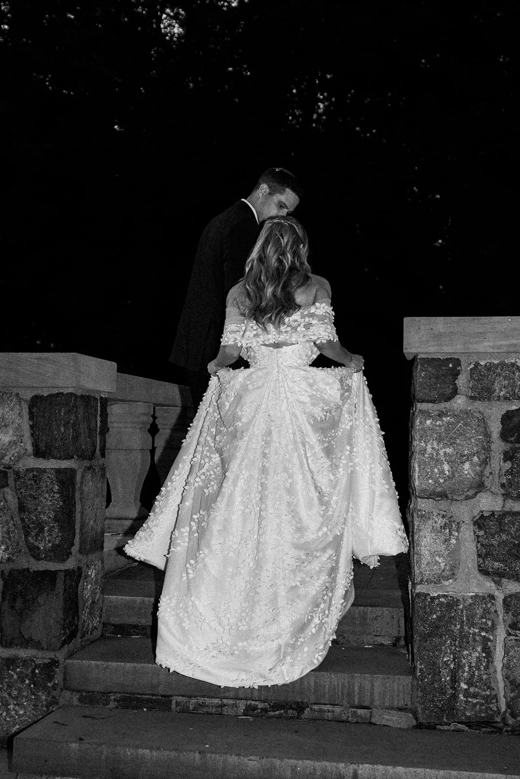 Groom helping his bride up the staircase during a quiet moment at their wedding celebration