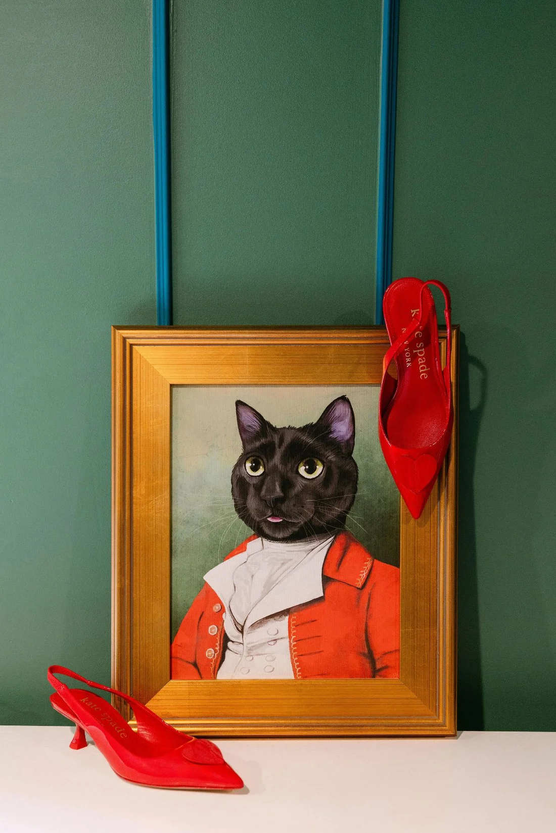 Bride’s red Kate Spade heels displayed with a whimsical cat painting before an outdoor wedding in New York
