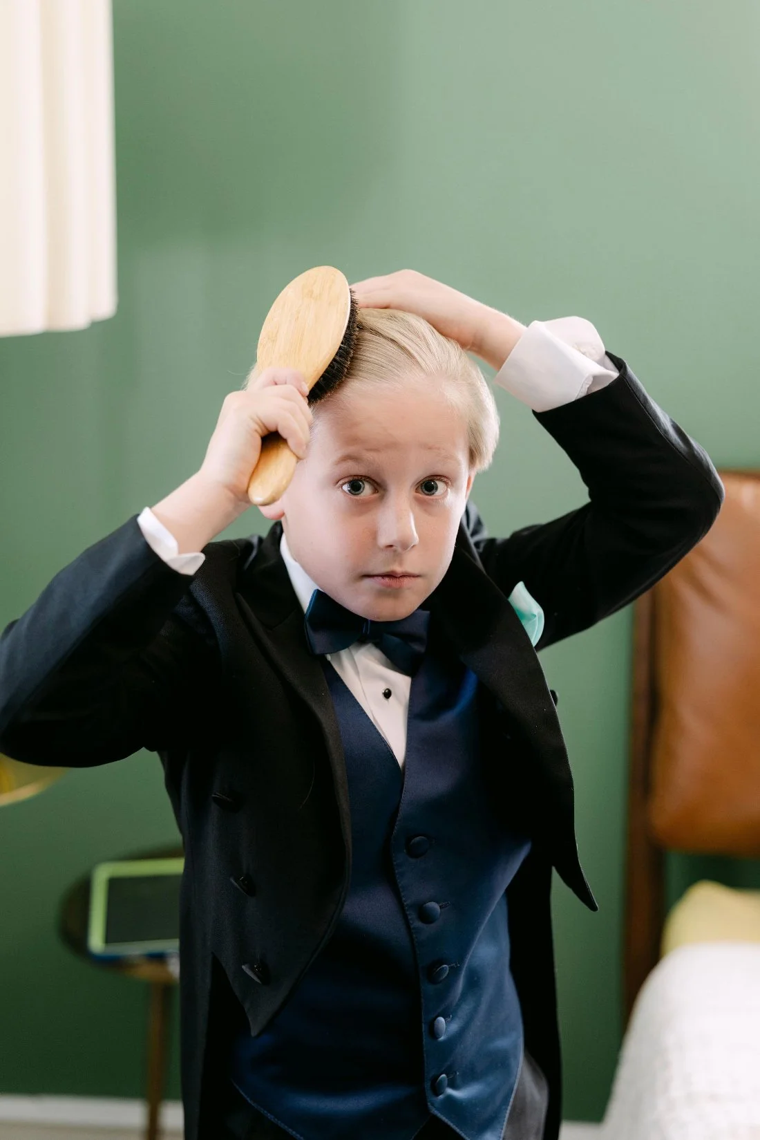 oung ring bearer getting ready in tuxedo for outdoor wedding in New York