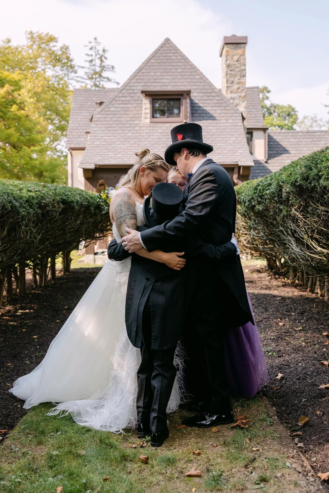 Bride, groom, and their children sharing a group hug in the garden before their outdoor wedding in New York
