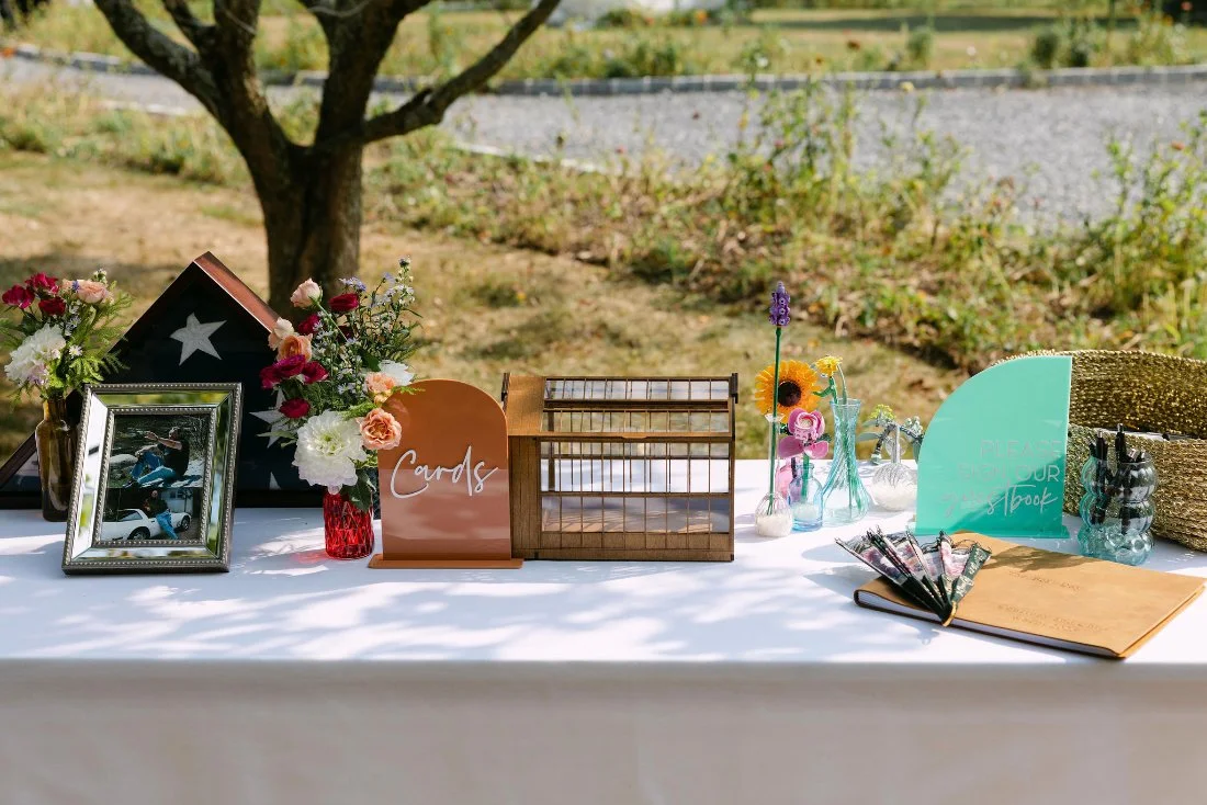 Wedding welcome table with cards box, floral decor, guestbook, and family photos at outdoor wedding in New York