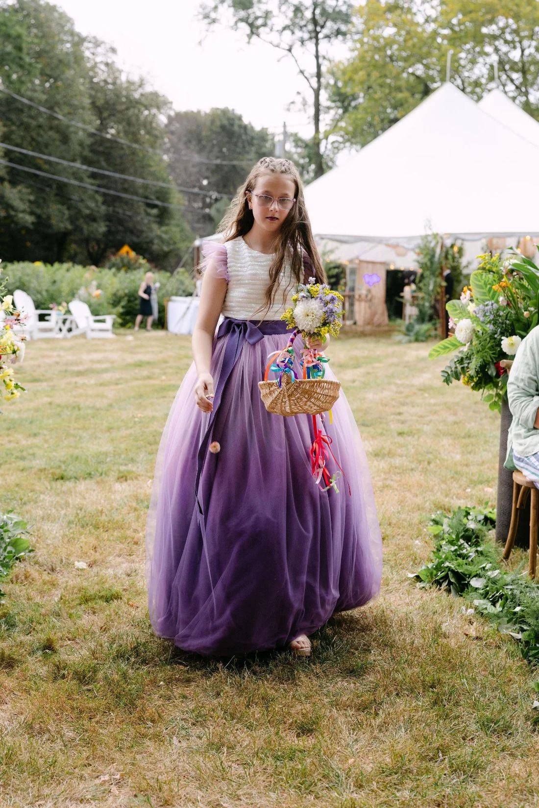 Flower girl walking down the aisle with a flower basket at whimsical outdoor wedding in New York