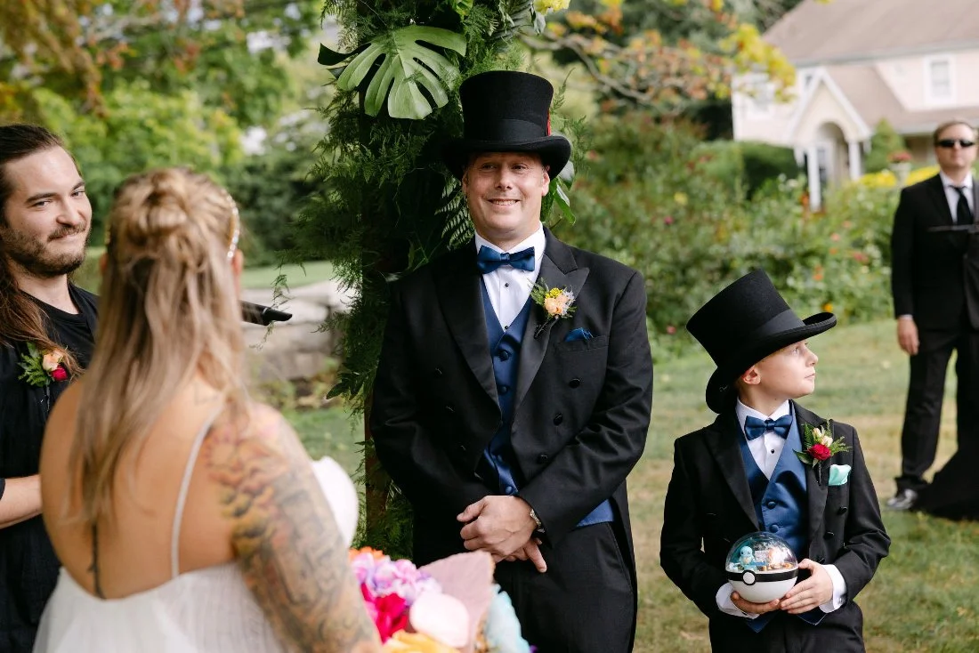 Groom and ring bearer standing at the altar in matching tuxedos during outdoor wedding ceremony in New York