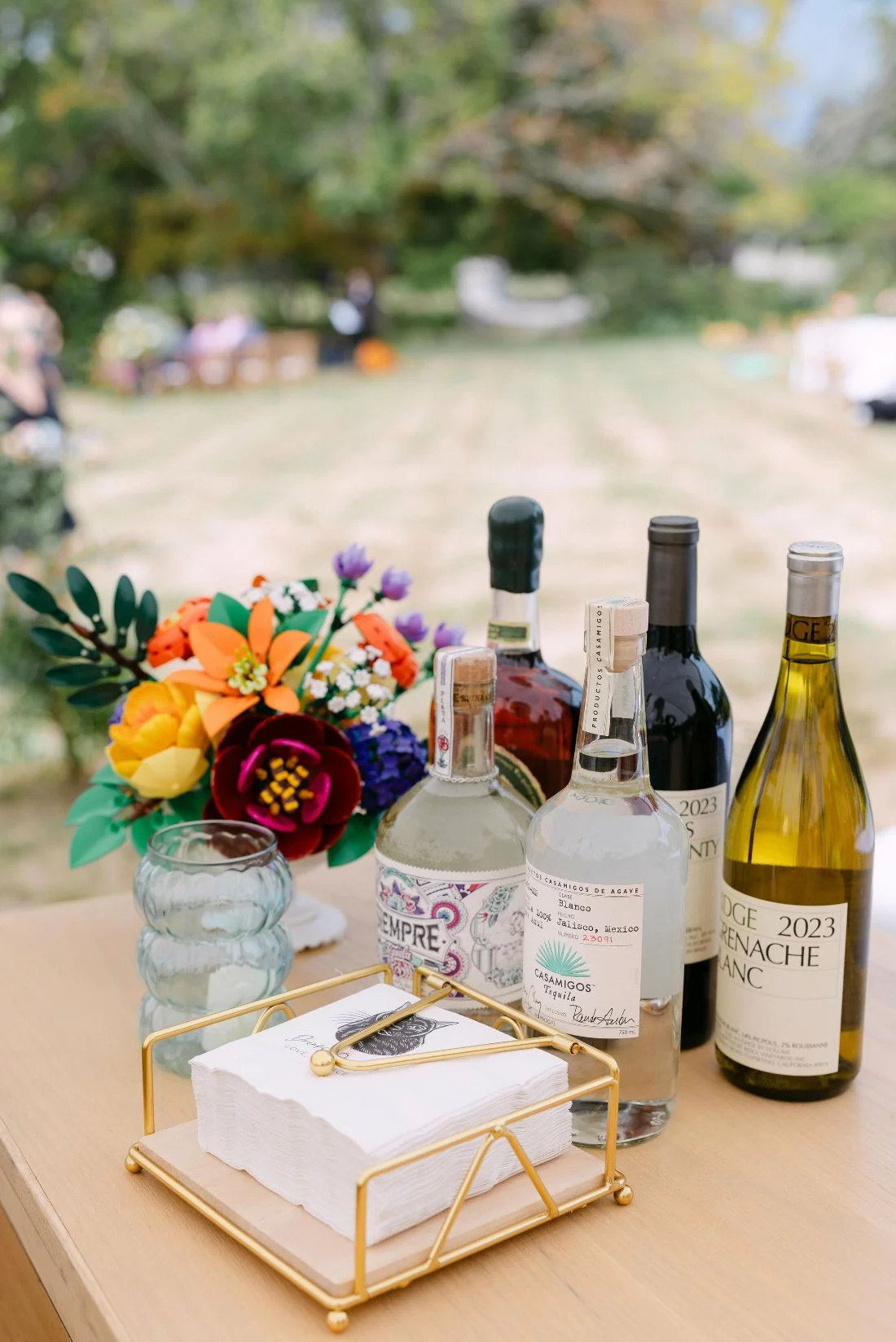 Colorful cocktail station with tequila, wine, and paper florals during outdoor wedding in New York