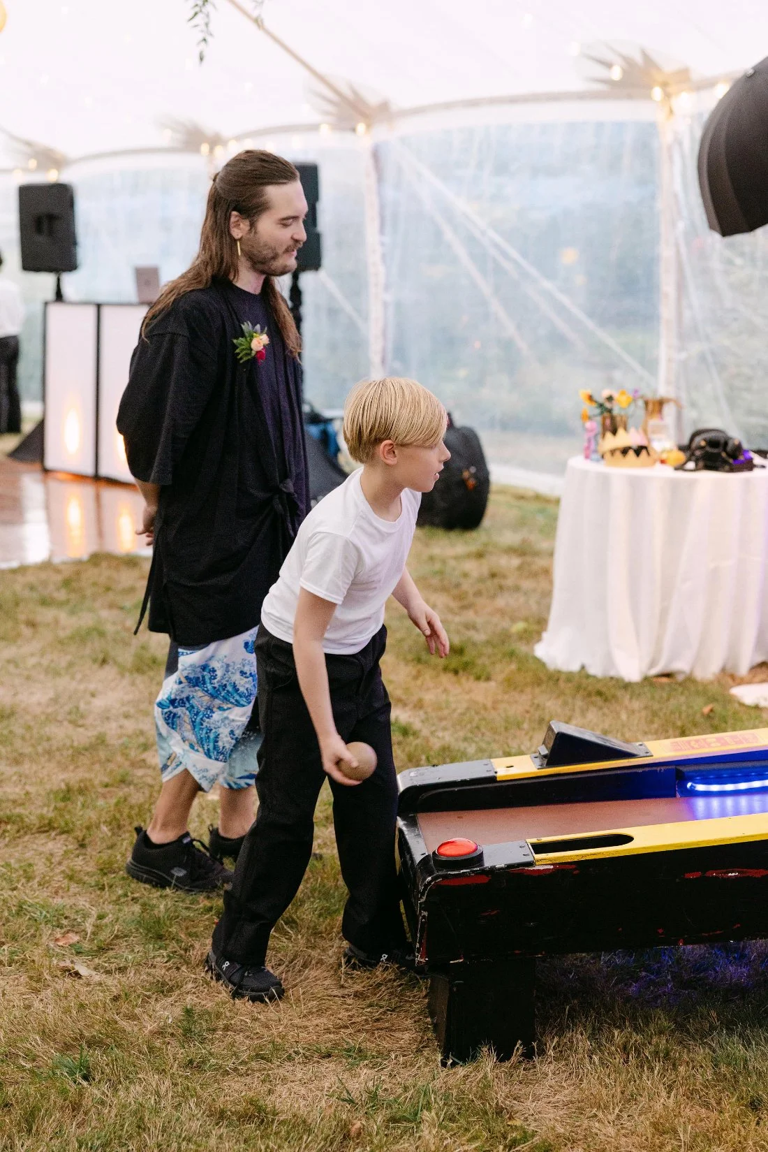 Young guest playing skee-ball during the tented reception at an outdoor wedding in New York
