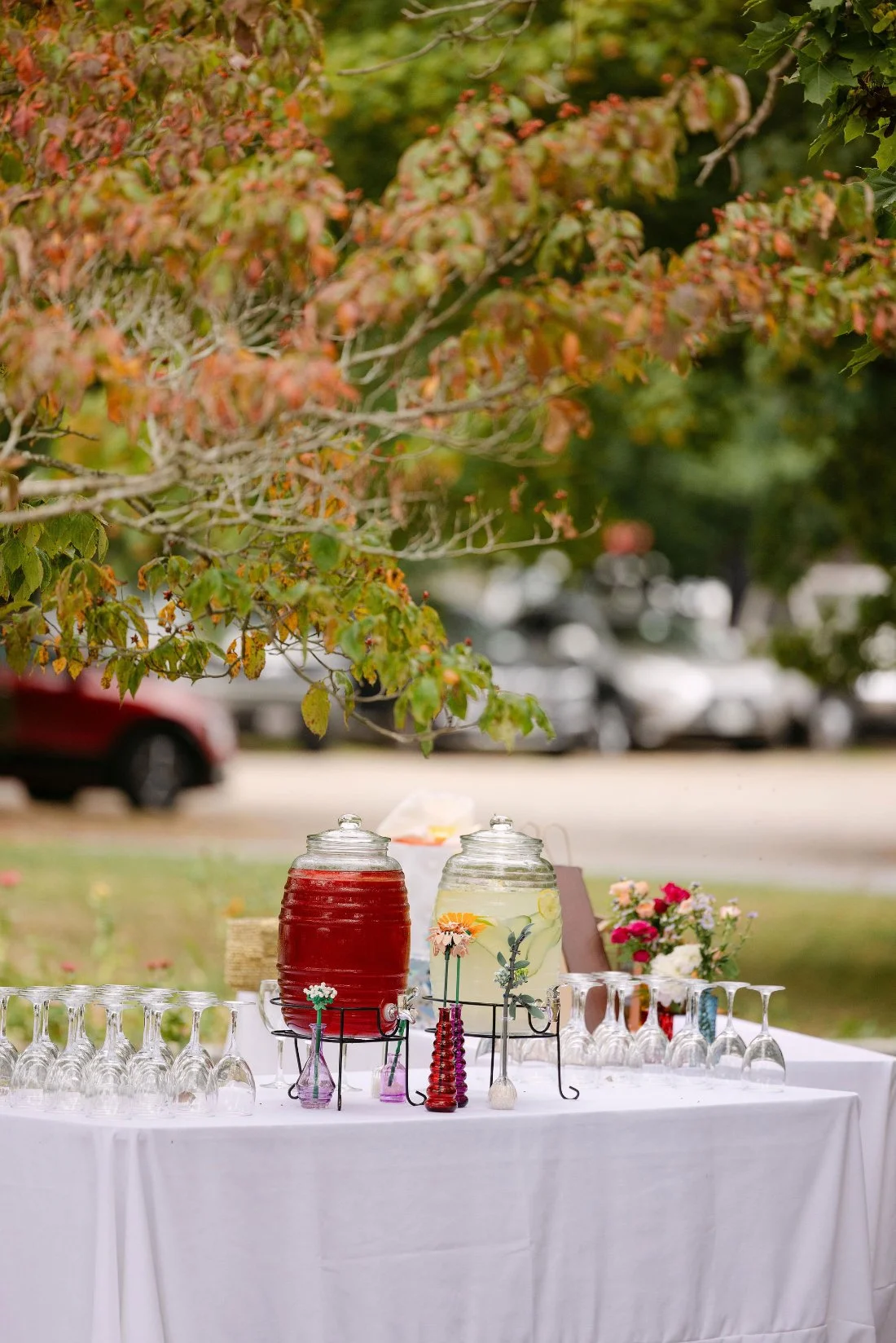 Self-serve beverage table with glass drink dispensers and vintage vases at outdoor wedding in New York