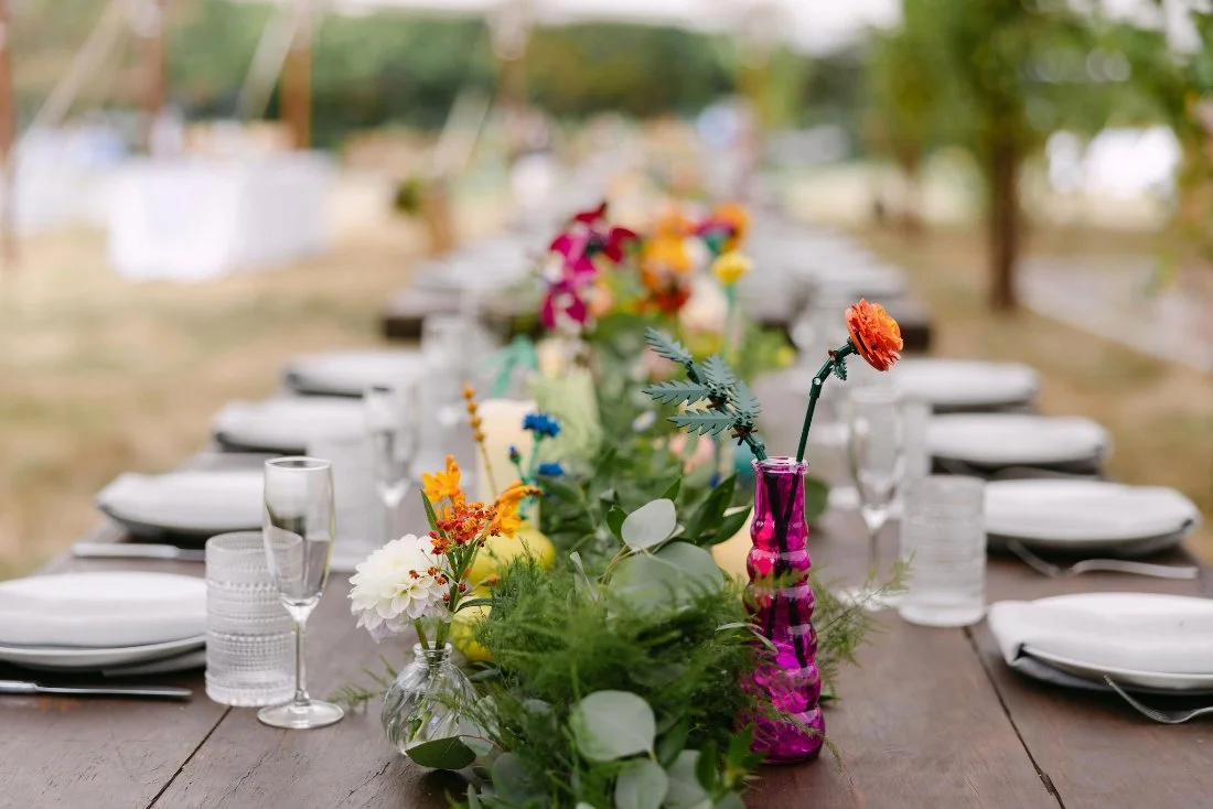 Colorful, whimsical table setting with floral arrangements at an outdoor wedding in New York
