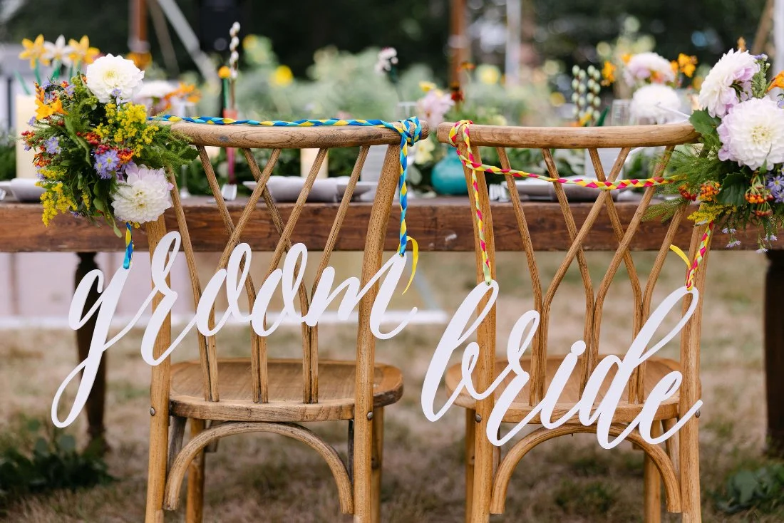 Wooden bride and groom chairs decorated with florals at an outdoor wedding in New York