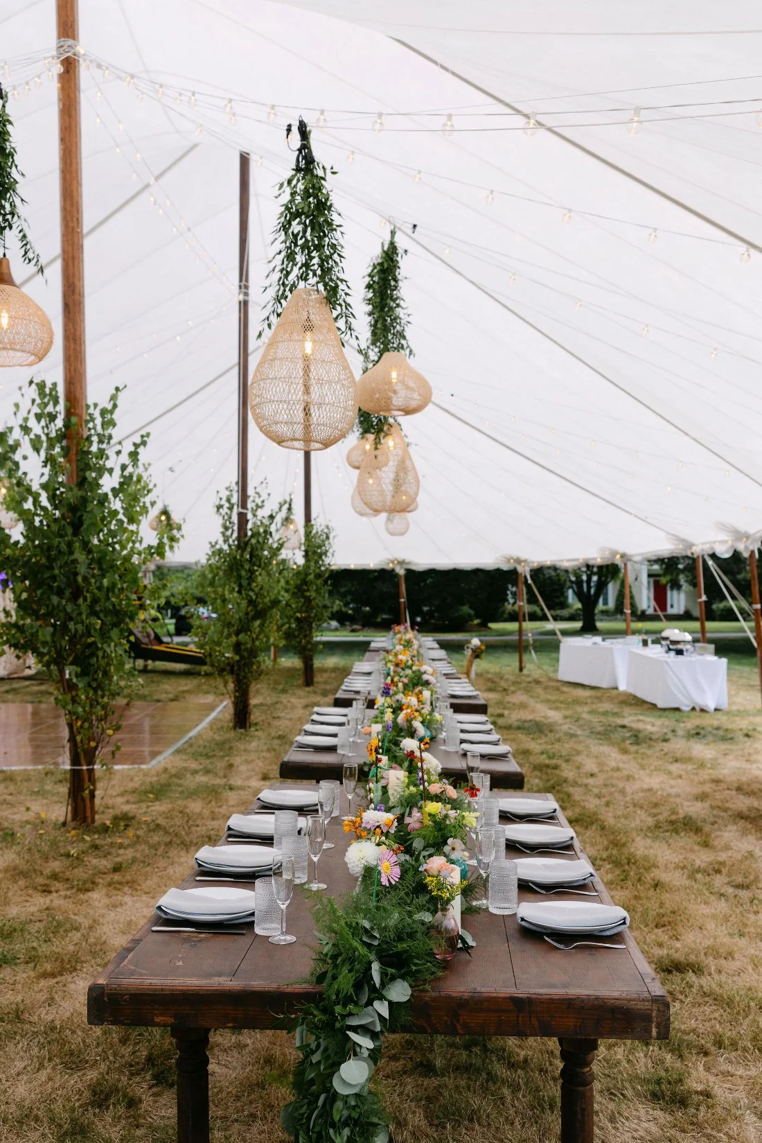 Elegant table set under a clear tent surrounded by greenery during an outdoor wedding in New York