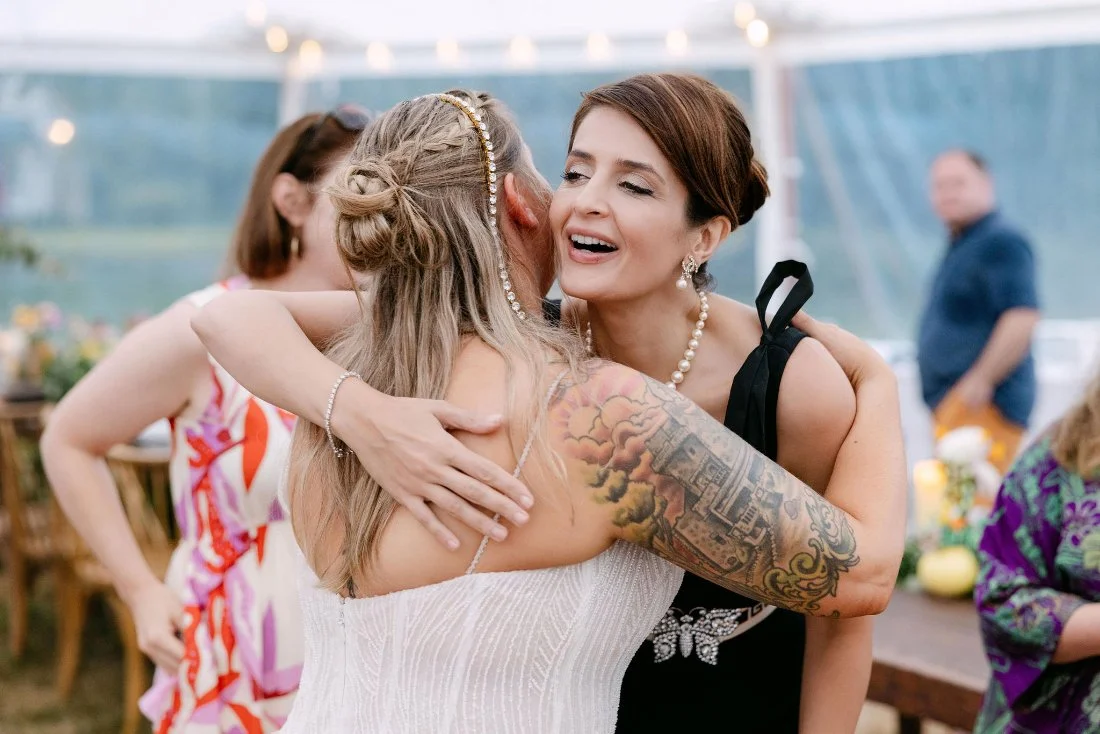Close friend warmly hugging the bride during the reception at an outdoor wedding in New York