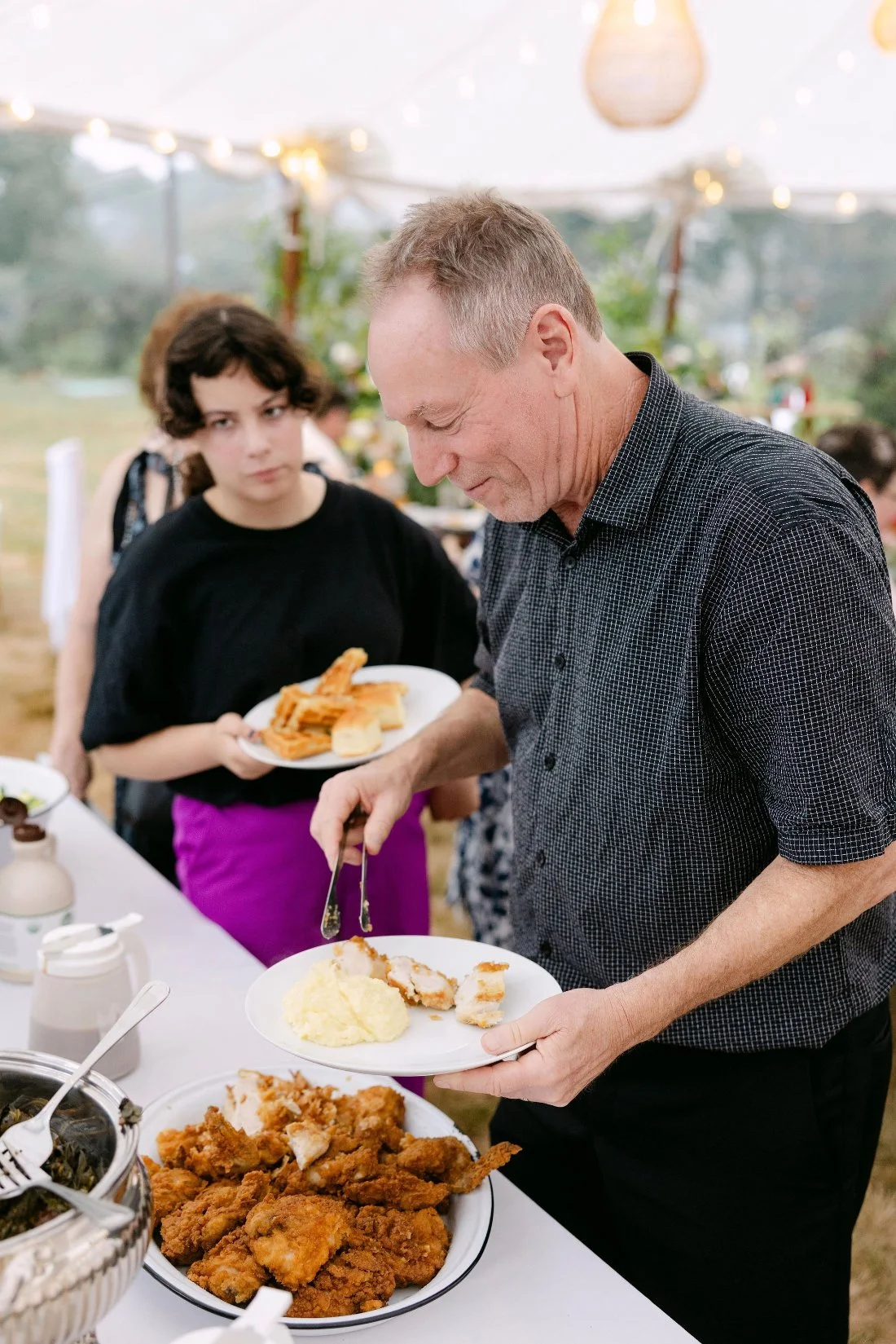 Guests serving themselves from a Southern-inspired buffet at an outdoor wedding in New York