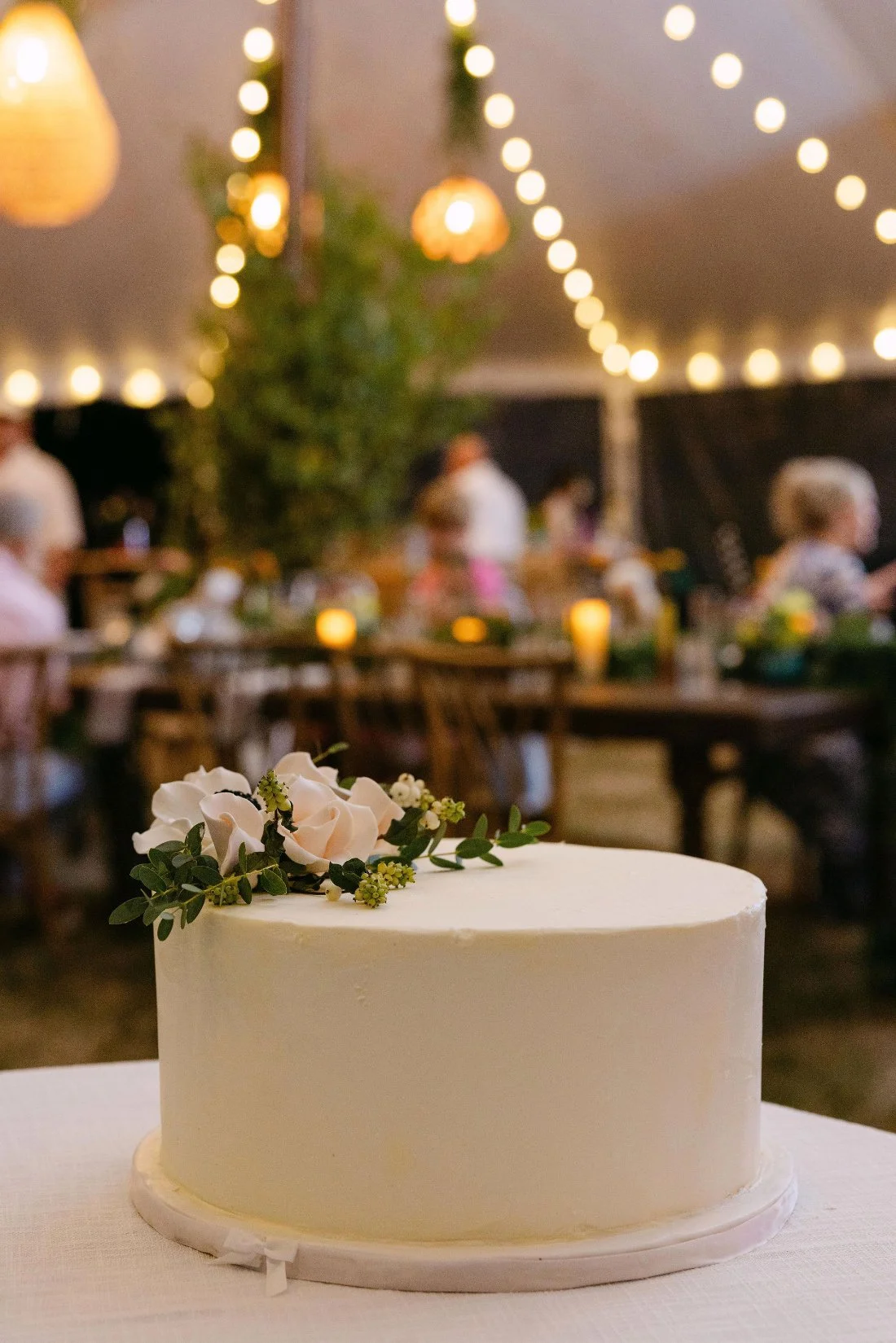 Three-tiered wedding cake displayed with fresh flowers at an outdoor wedding in New York