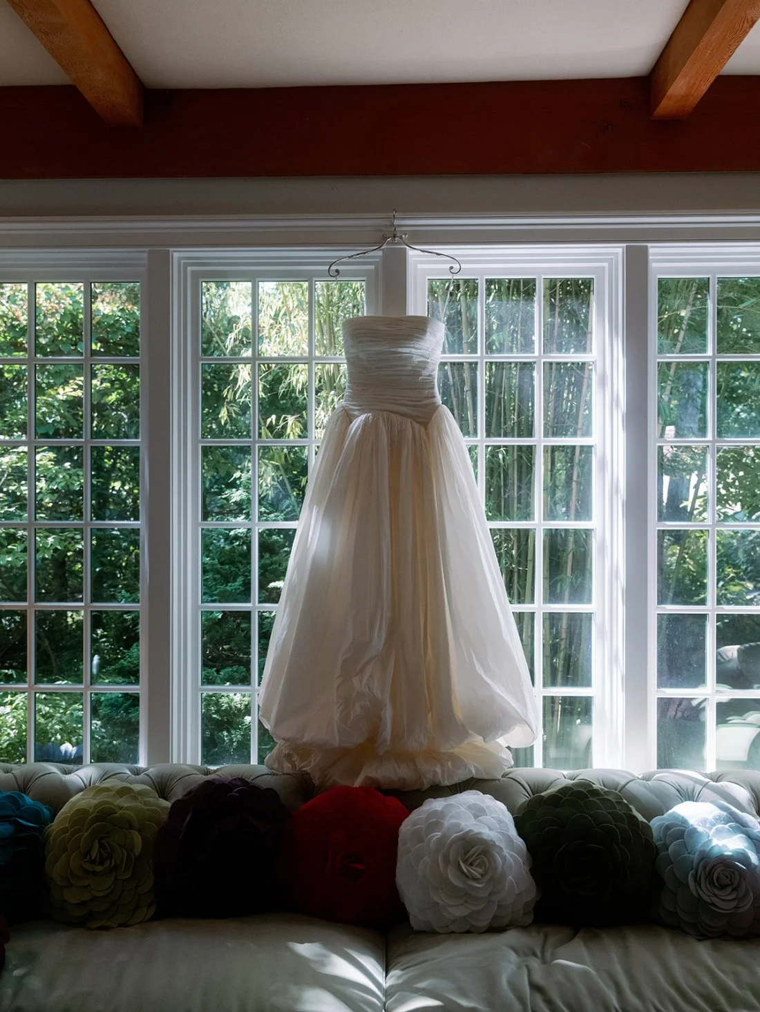 Bride’s wedding dress hanging in a bright window before her Hamptons wedding celebration.