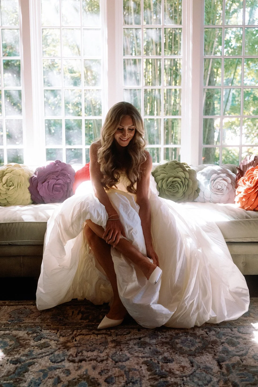 Bride putting on her wedding shoes in a bright window at her Hamptons wedding private residence.