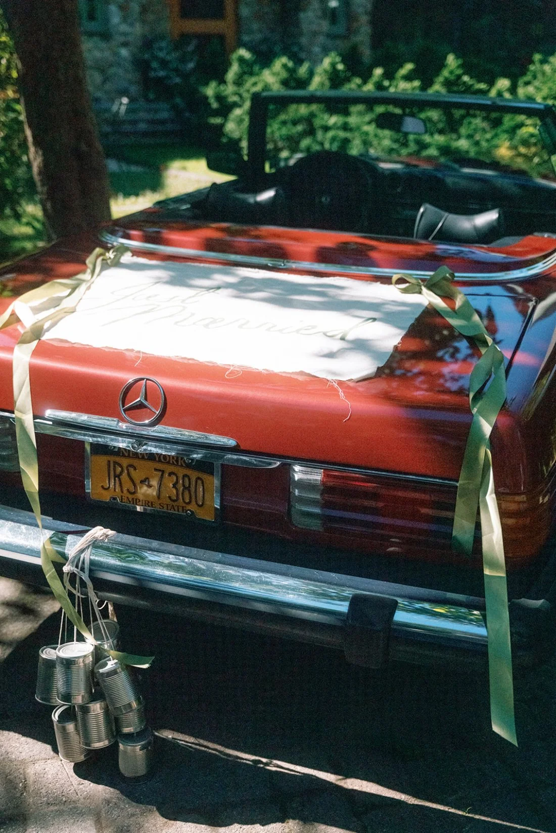 Vintage red convertible with “Just Married” sign and dangling cans at a Hamptons wedding celebration.