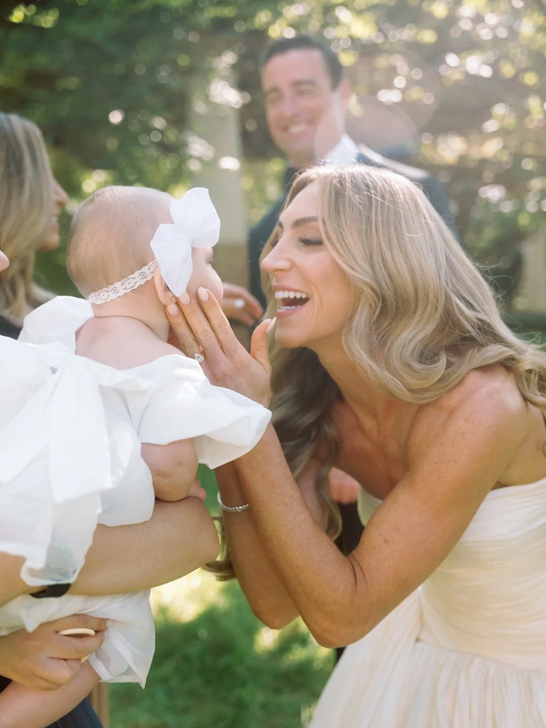 Bride meeting a newborn baby and young children during her Hamptons wedding celebration.