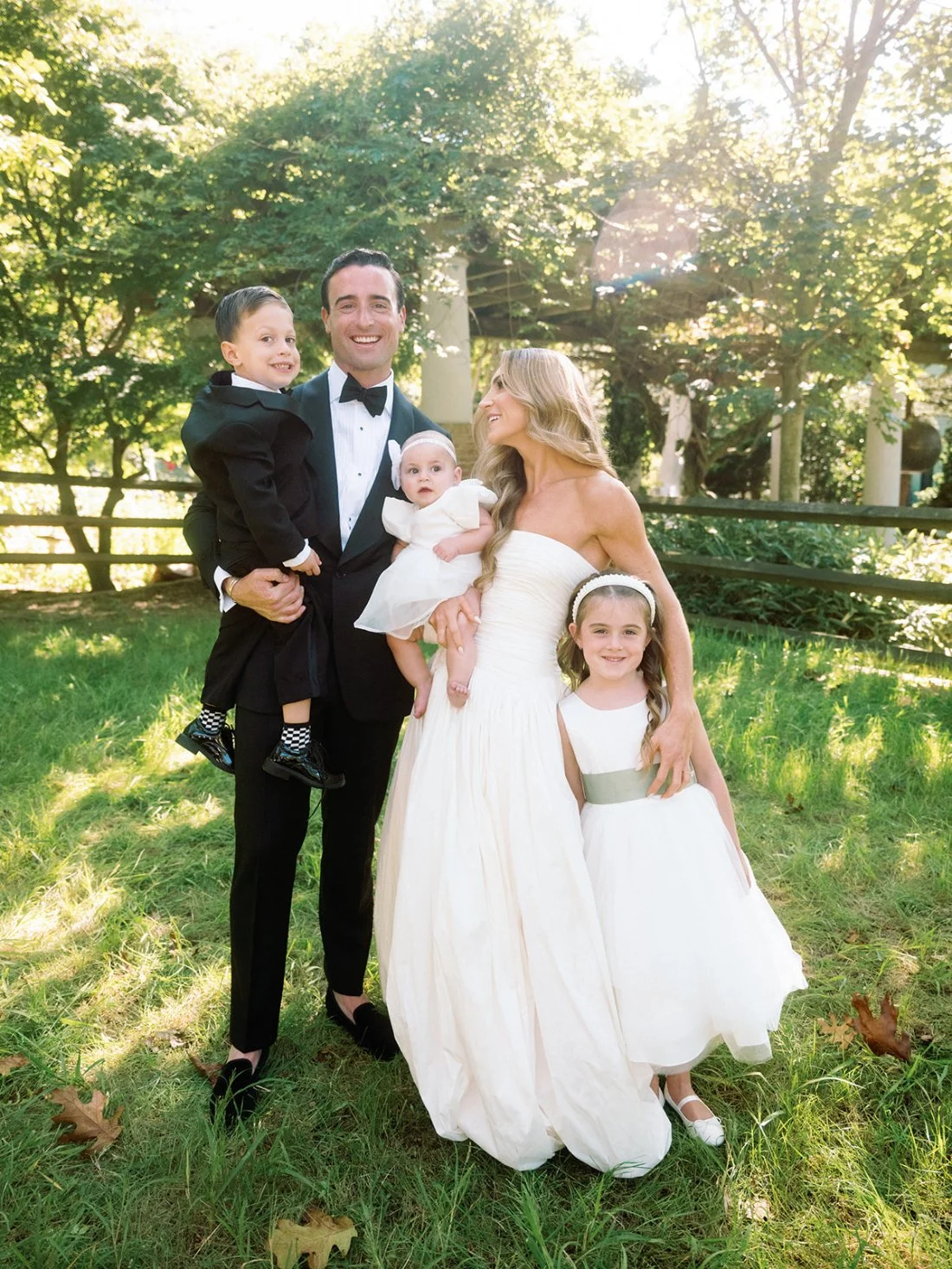 Bride and groom taking photos with three young children, flower girls, and ring bearer at their Hamptons wedding.