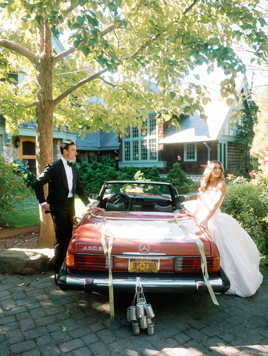 Bride and groom posing with a vintage red convertible at their Hamptons wedding.