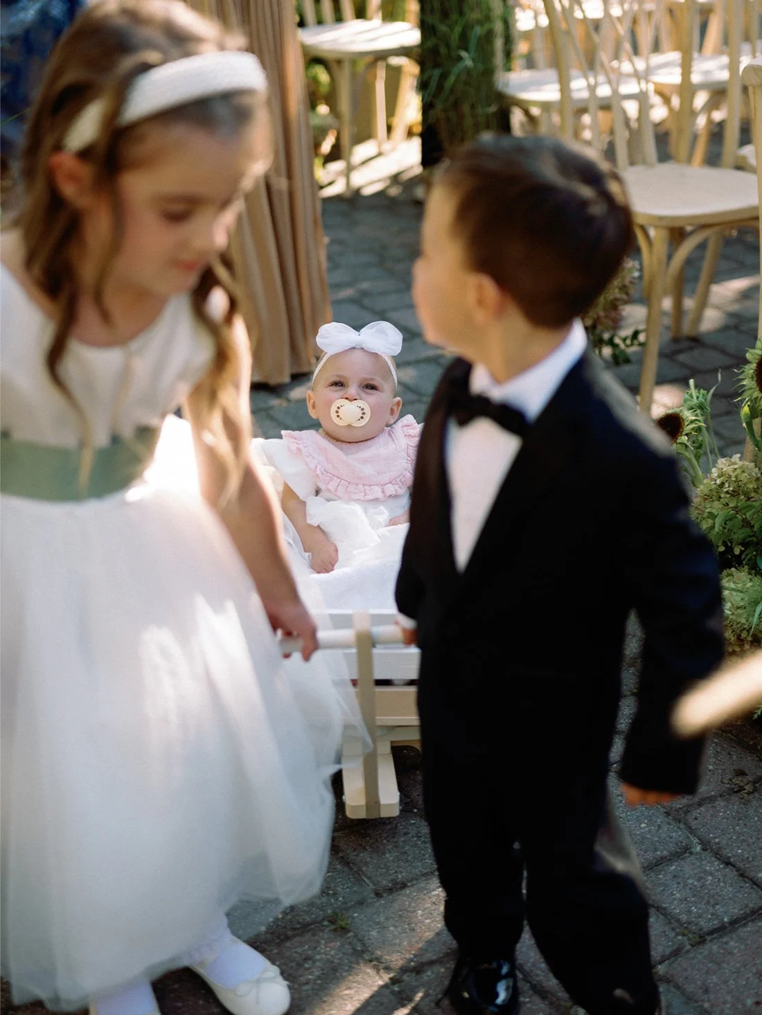 Flower girl and ring bearer pulling a baby in a wagon down the aisle at a Hamptons wedding.