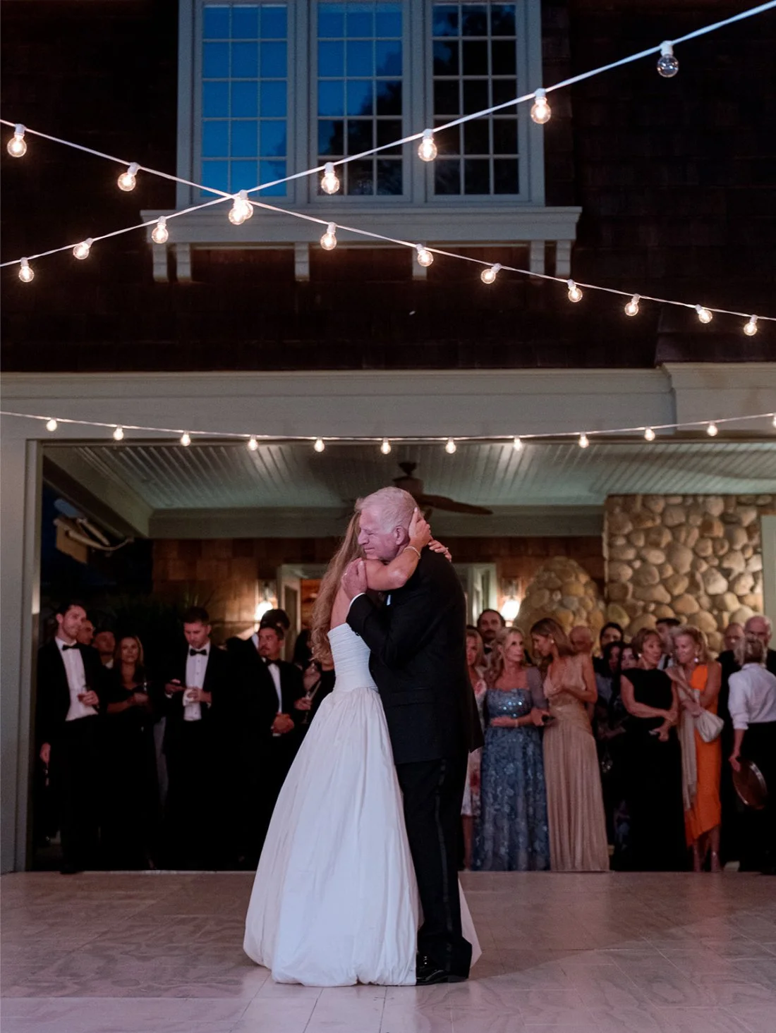 Bride dancing with her father under string lights outside during their Hamptons wedding reception.