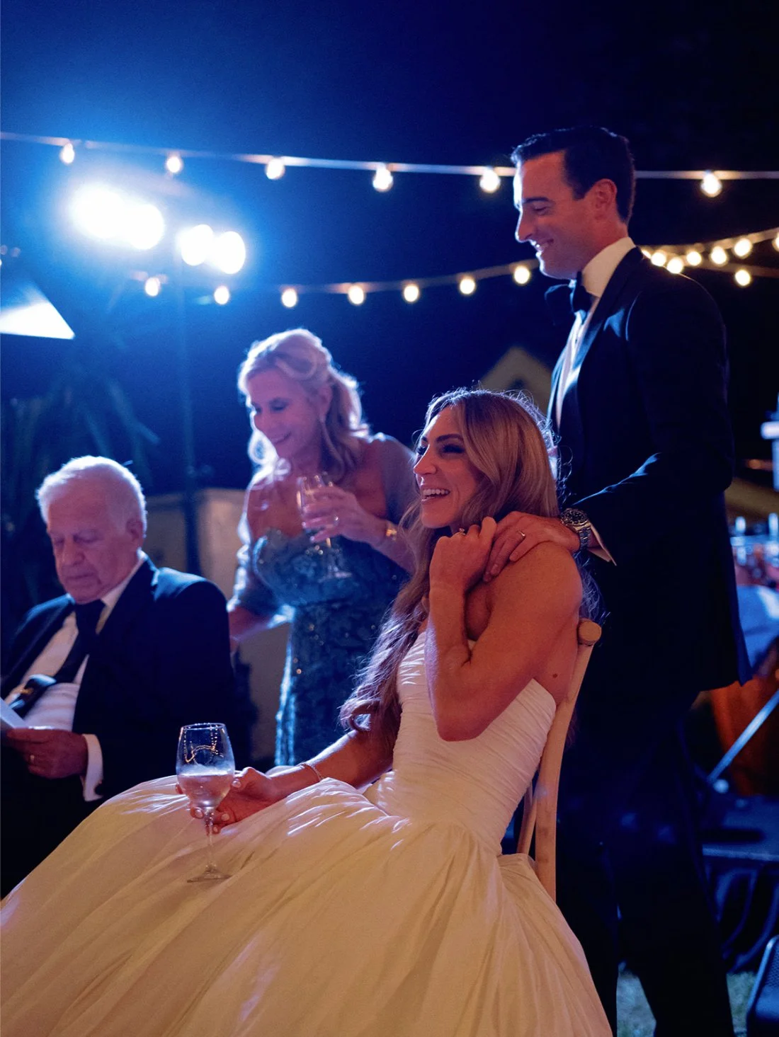 Bride and groom watching their guests laugh and dance during their Hamptons wedding reception.