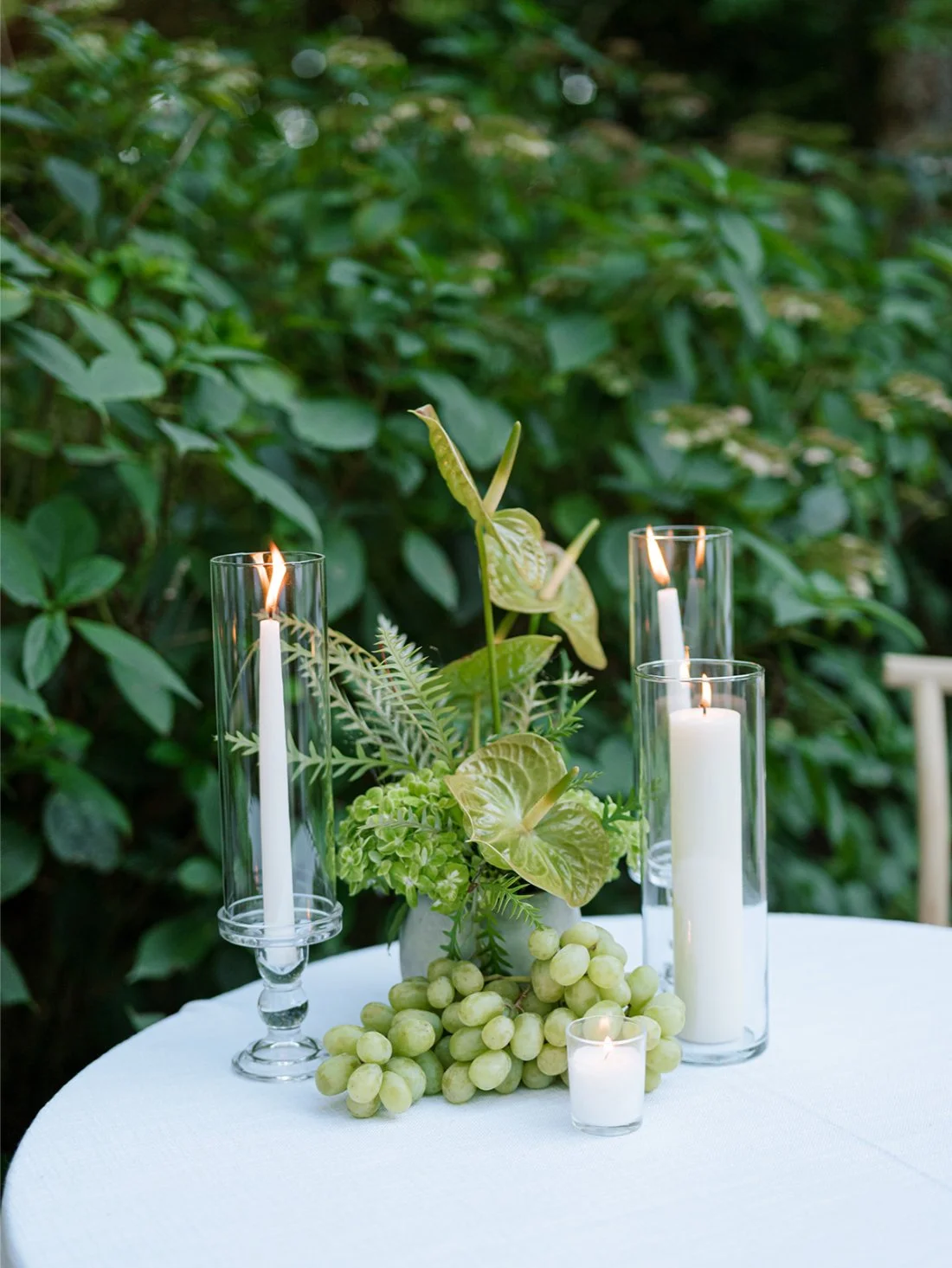 Candlelit cocktail table centerpiece with green florals and grapes at an elegant Hamptons wedding.