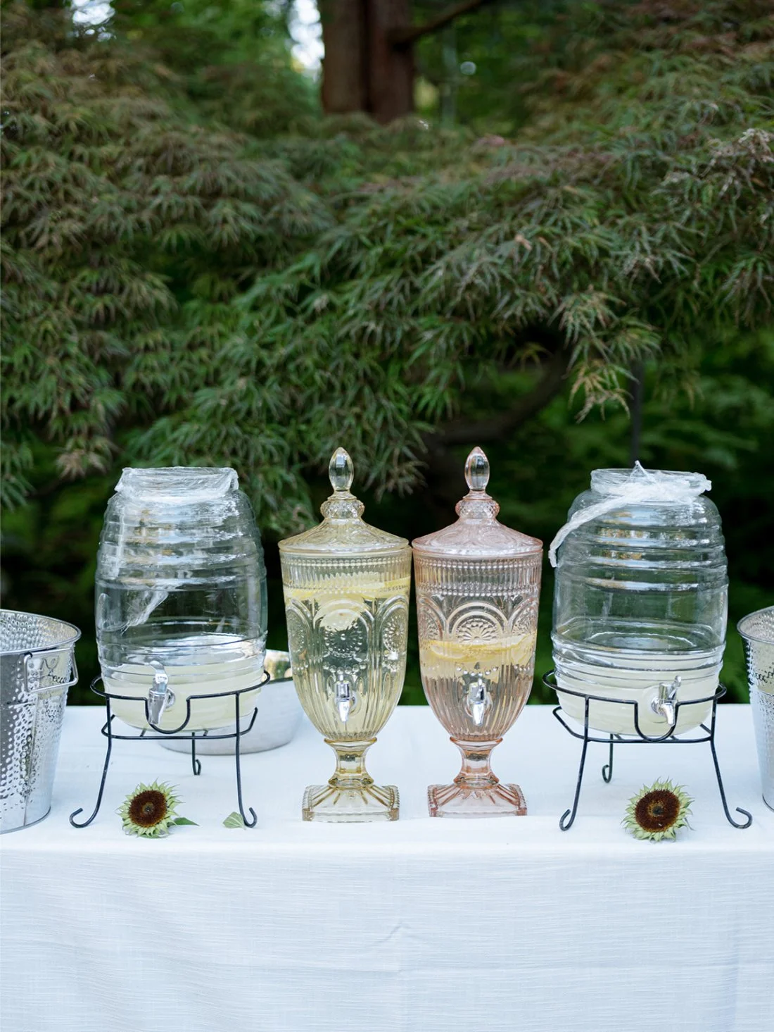 Vintage-style glass beverage dispensers set up for guests at an outdoor Hamptons wedding.