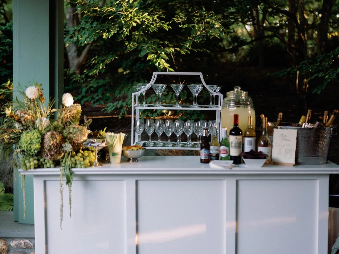 Elegant outdoor bar setup with glassware and florals at a private residence Hamptons wedding.