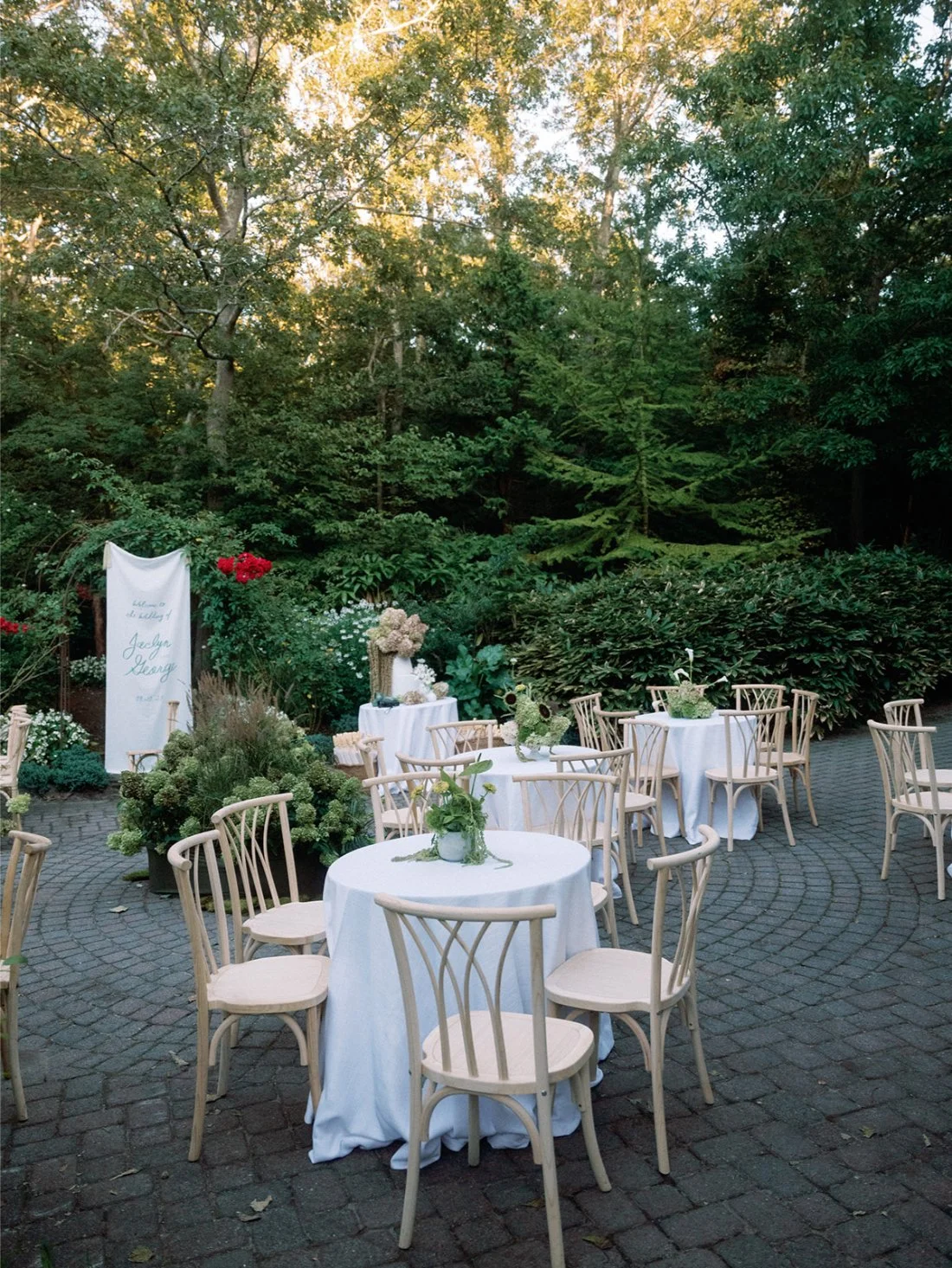 Outdoor cocktail tables arranged on a stone patio at a Hamptons wedding in Water Mill.