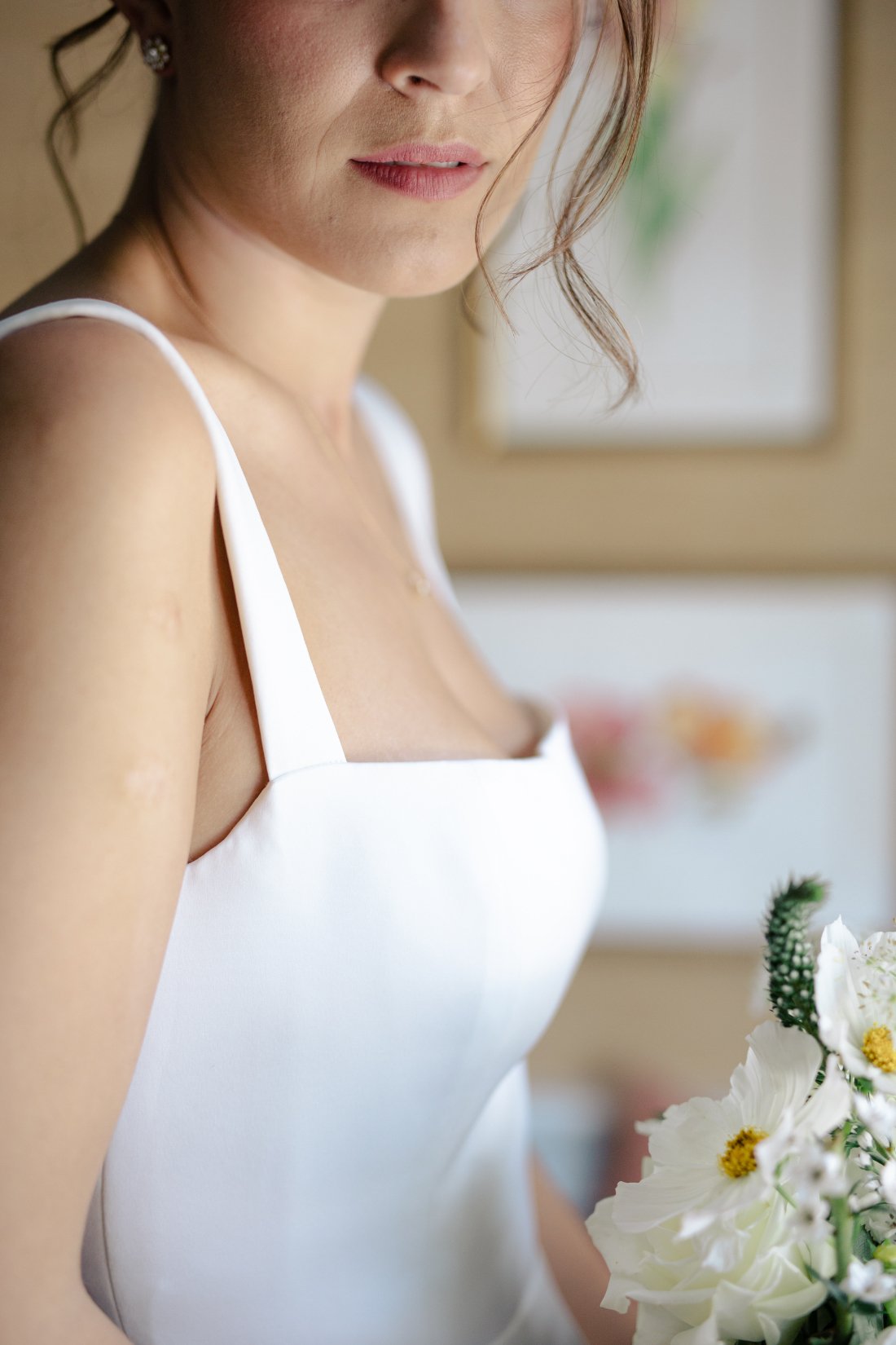 Close-up of modern square neckline wedding gown and bridal bouquet
