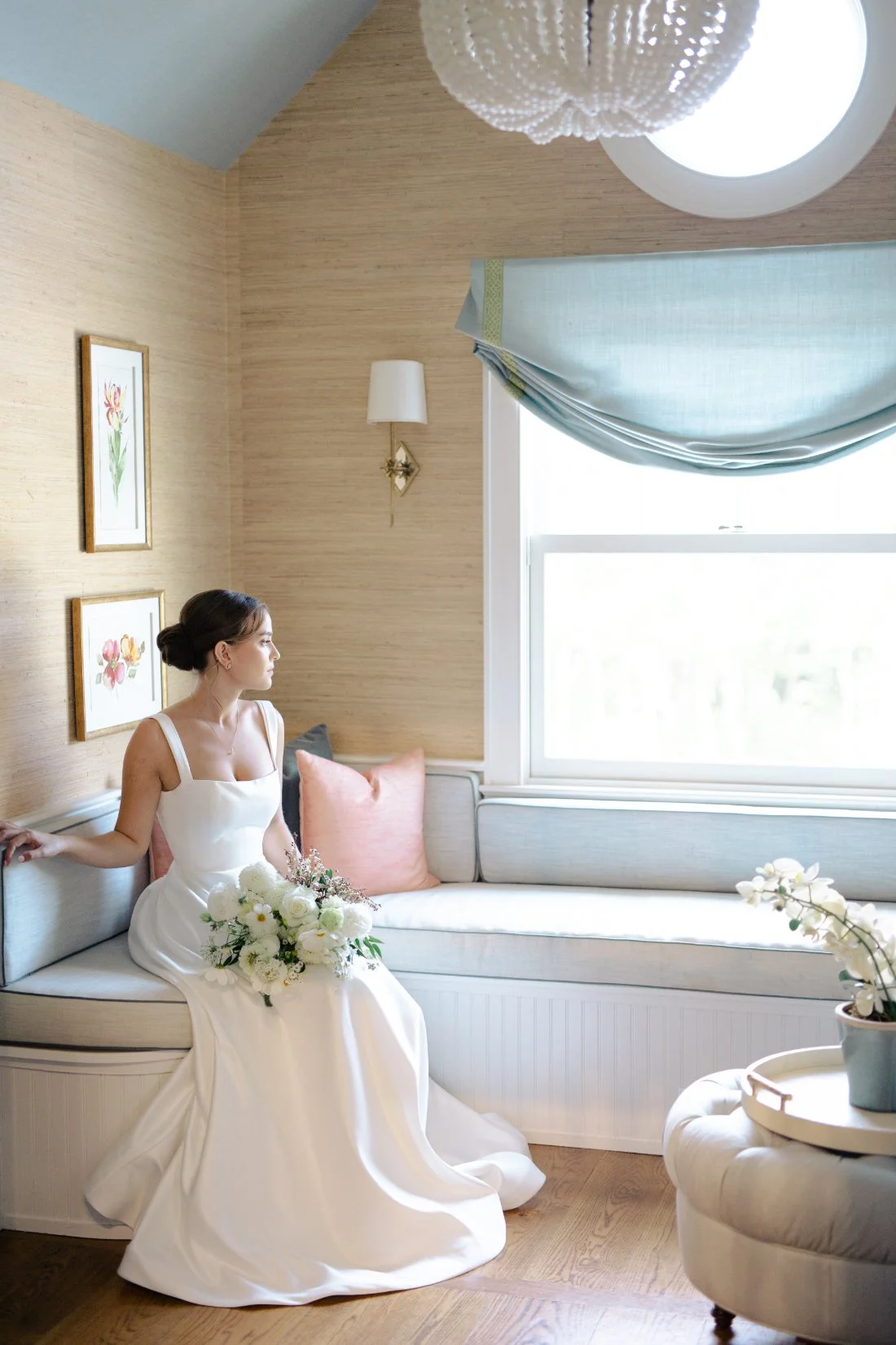 Bride sitting by window with bouquet in soft coastal light at Peconic Bay Yacht Club