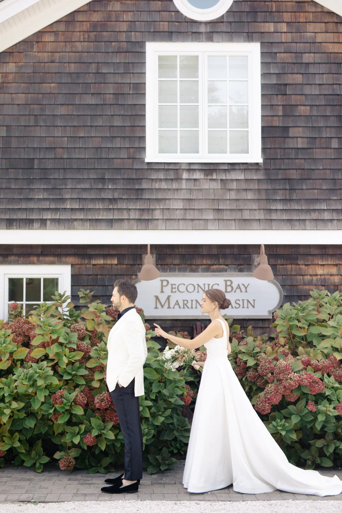 Bride approaching groom for first look in front of Peconic Bay Yacht Club sign