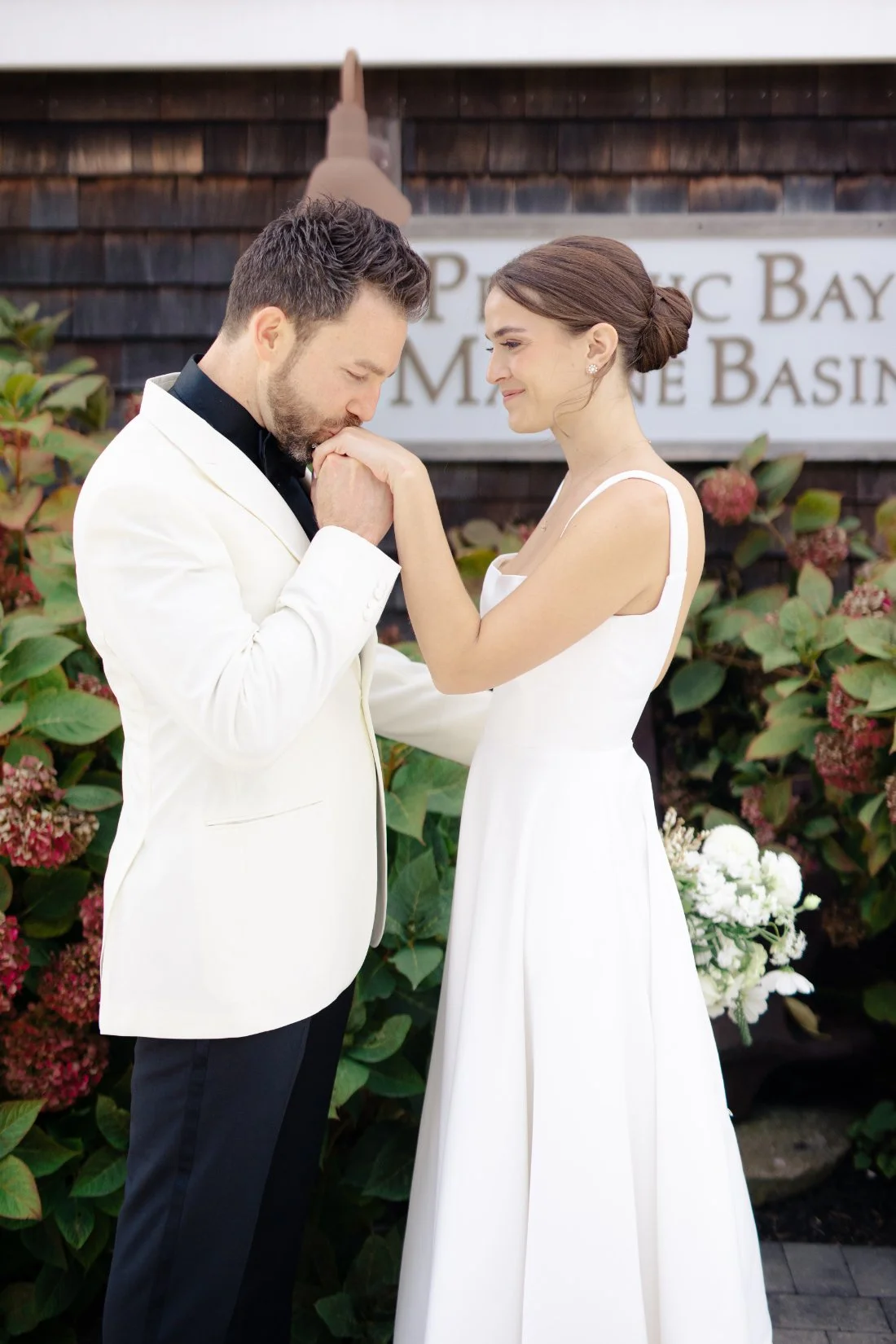 Groom kissing bride’s hand during romantic first look at Peconic Bay Yacht Club