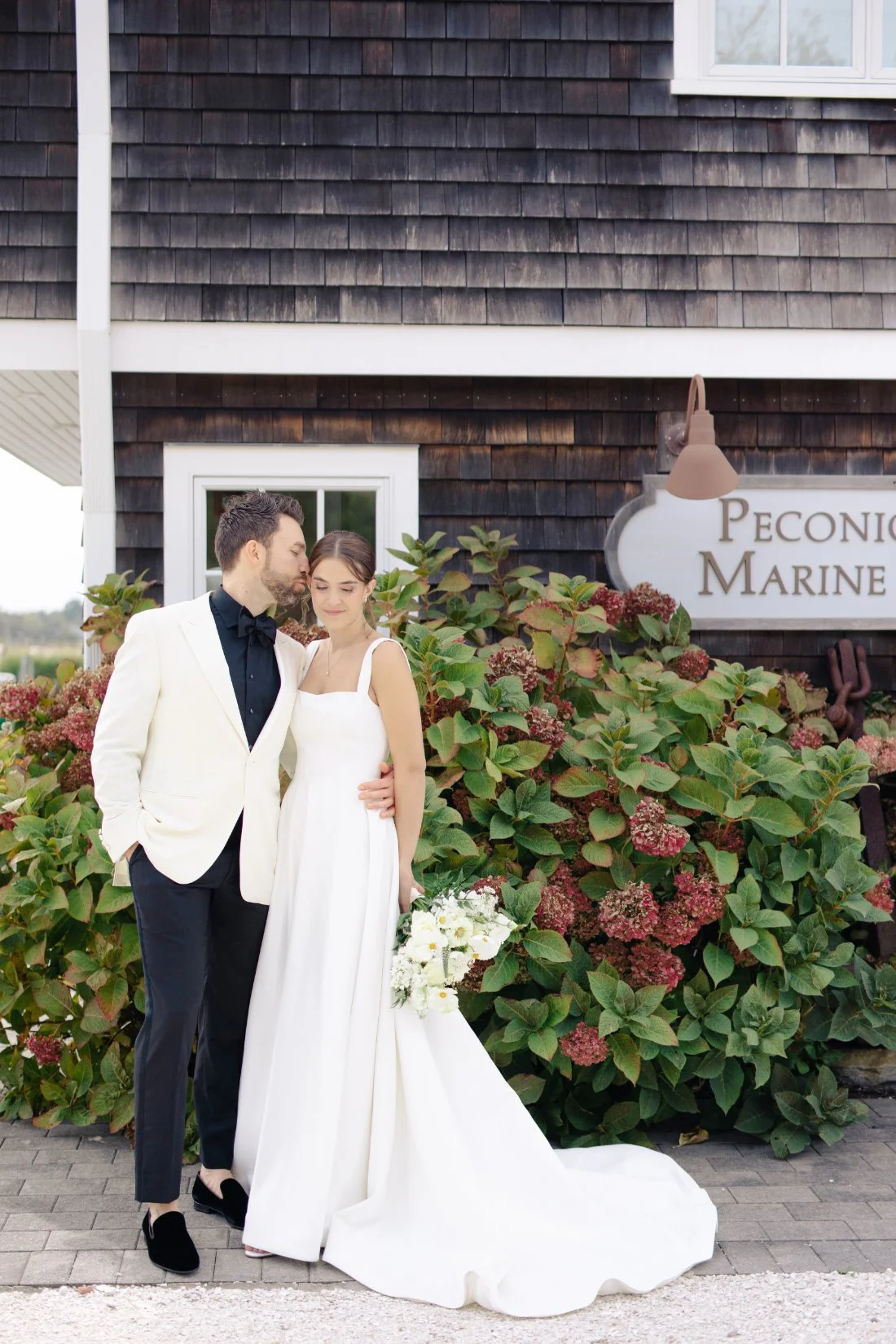 Bride and groom embracing with coastal hydrangeas at Peconic Bay Yacht Club