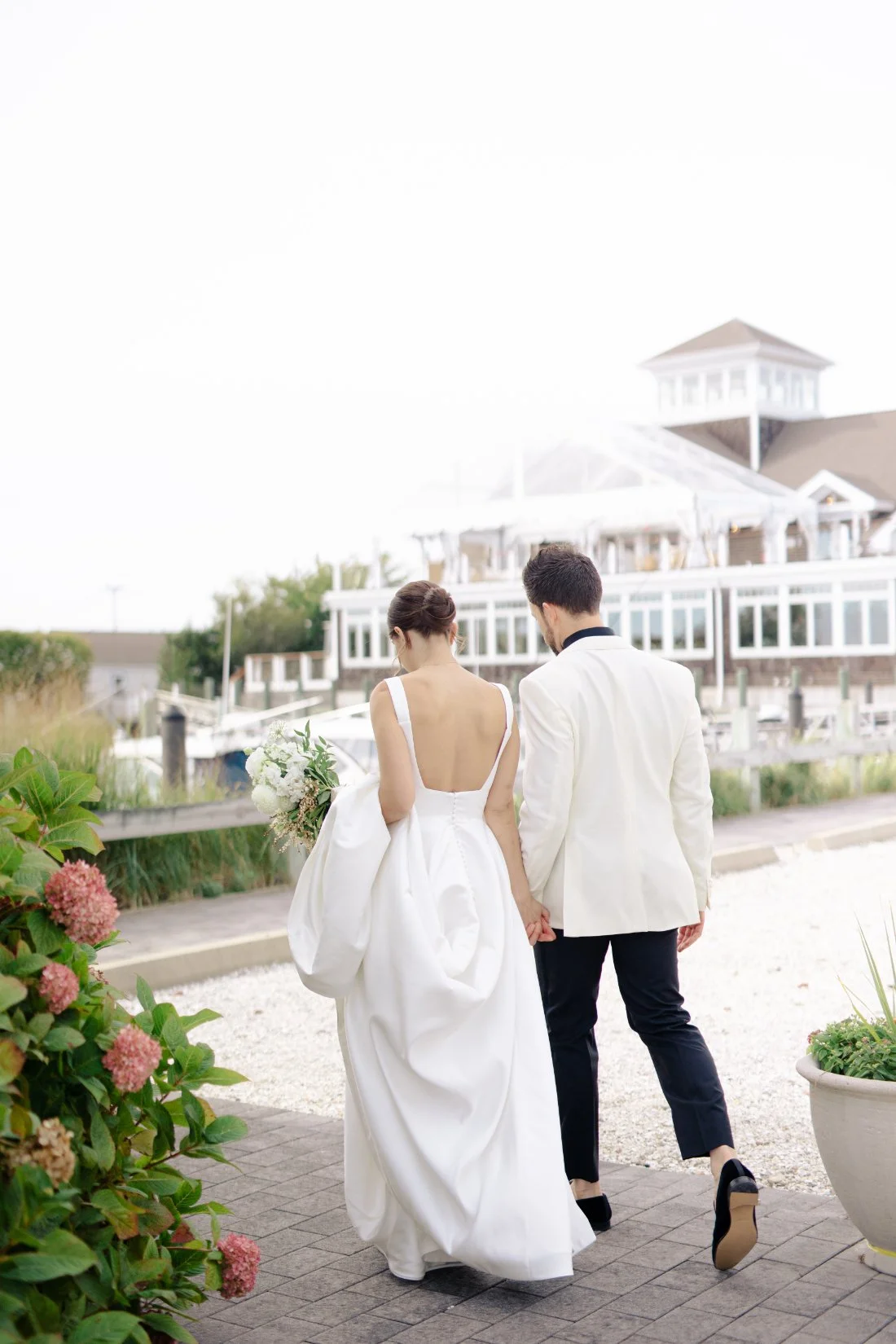 Newlyweds walking along marina at Peconic Bay Yacht Club wedding in Southold