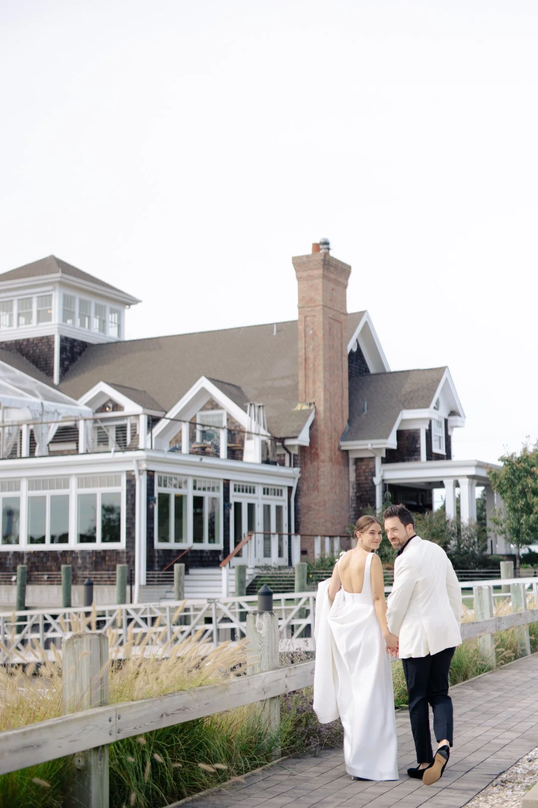 Couple walking by Peconic Bay Yacht Club with waterfront views and soft light