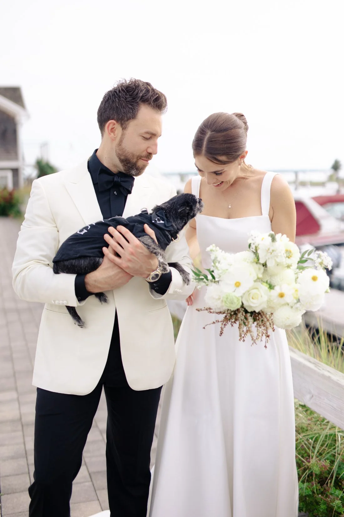 Bride and groom holding their dog during Peconic Bay Yacht Club wedding portraits