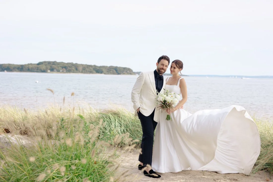 Couple walking by Peconic Bay Yacht Club with waterfront views and soft light