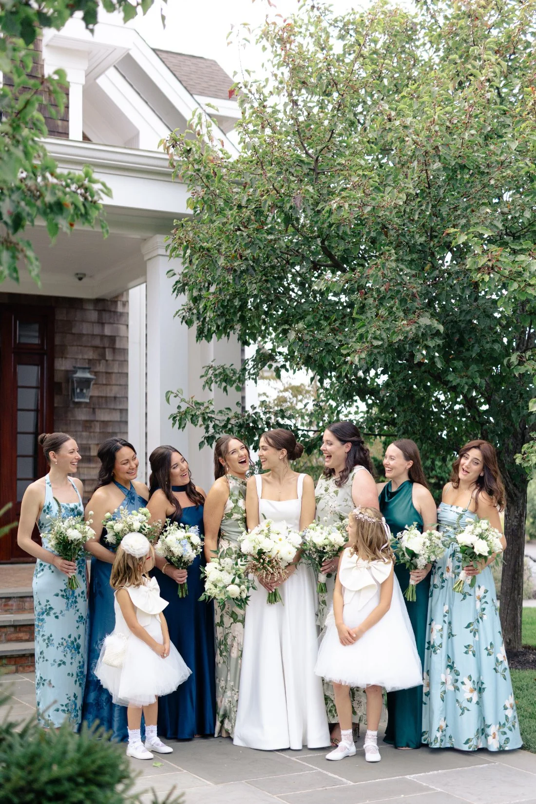 Bride laughing with bridesmaids and flower girls holding bouquets outside Peconic Bay Yacht Club
