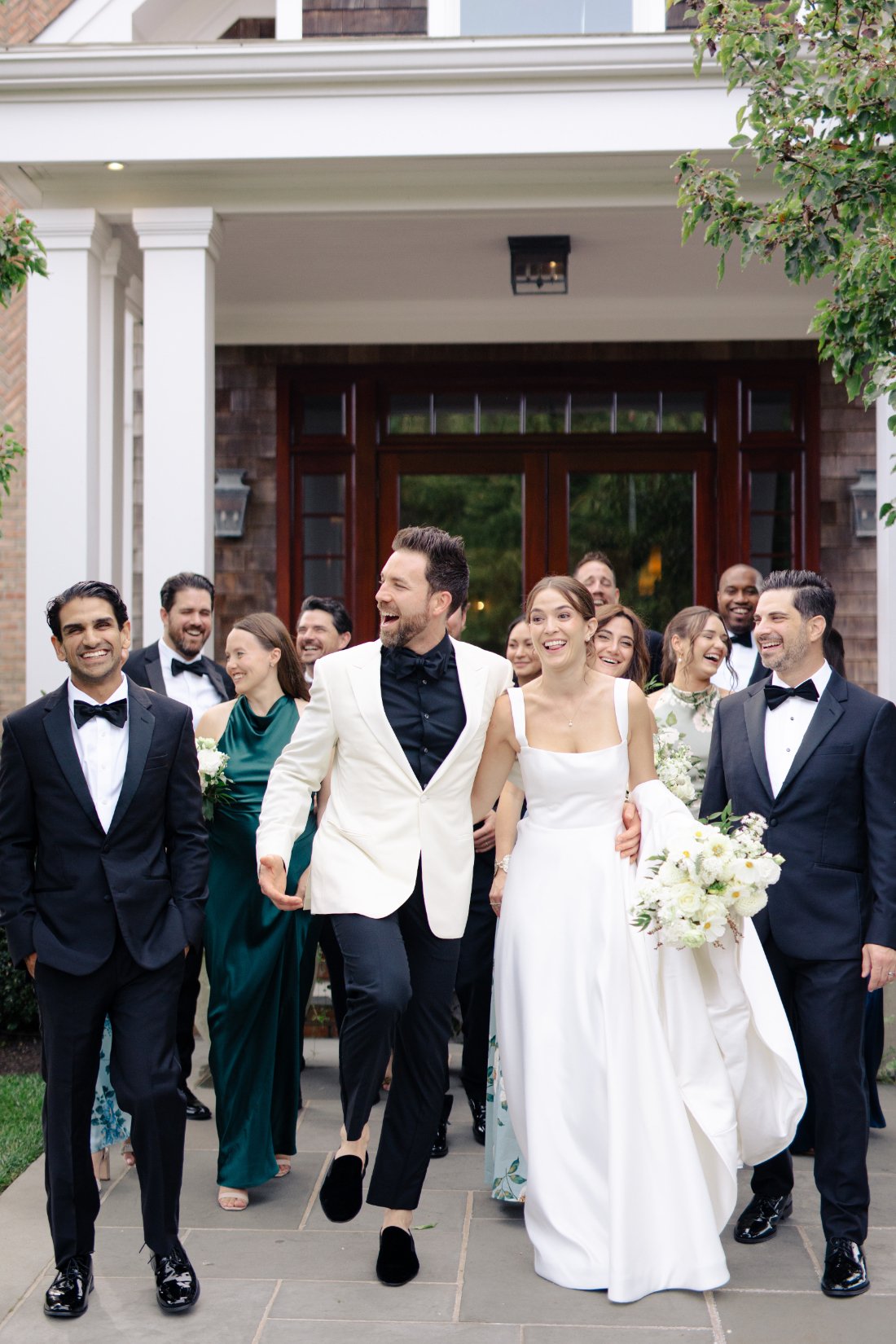 Bride and groom walking with wedding party outside Peconic Bay Yacht Club in Southold New York