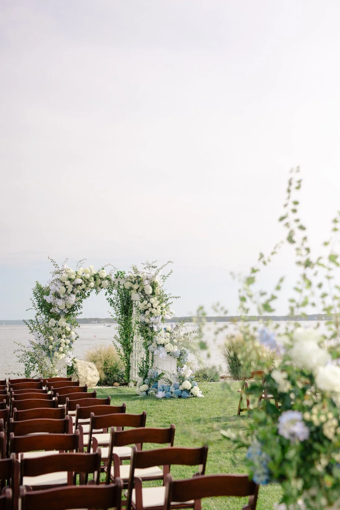 Waterfront ceremony setup with floral arch and chairs at Peconic Bay Yacht Club