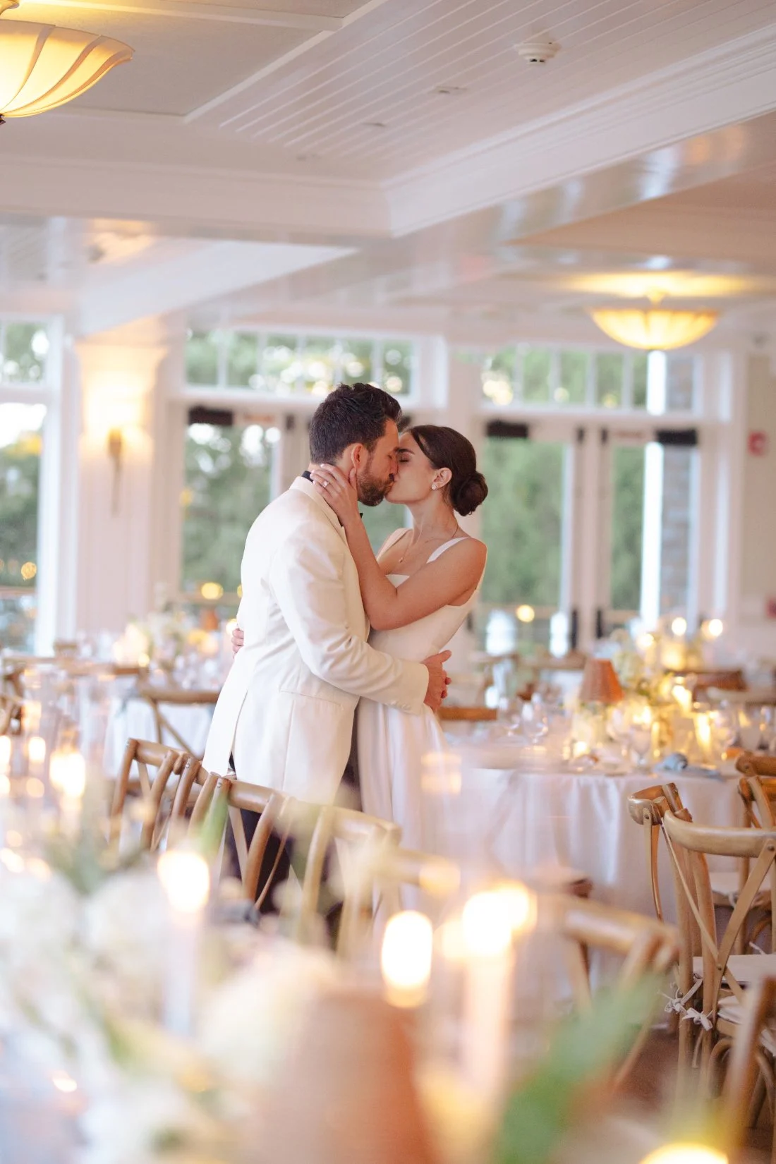 Bride and groom kissing in candlelit reception space at Peconic Bay Yacht Club