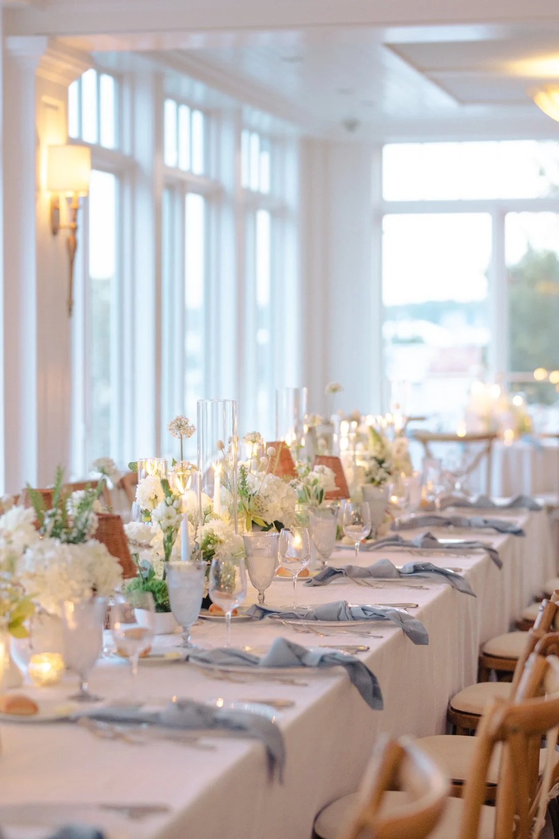 Long reception table with floral arrangements and candlelight at Peconic Bay Yacht Club