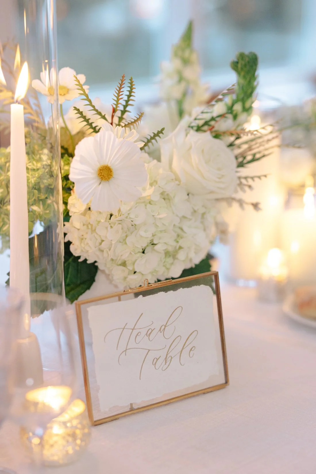 Head table sign with white floral arrangement and candle decor at Peconic Bay Yacht Club